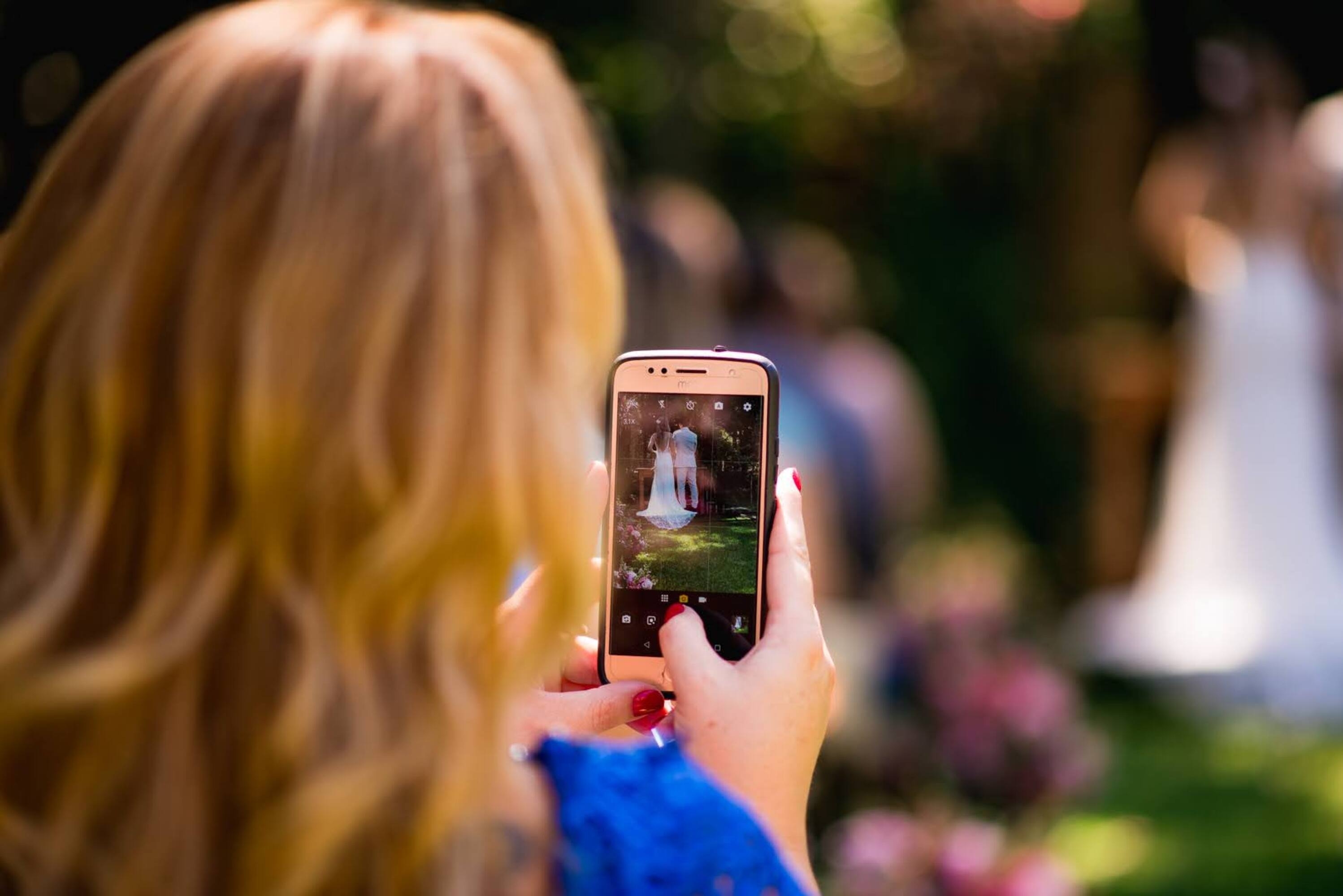 Una mujer haciendo una foto con su teléfono en una boda | Fuente: Shutterstock