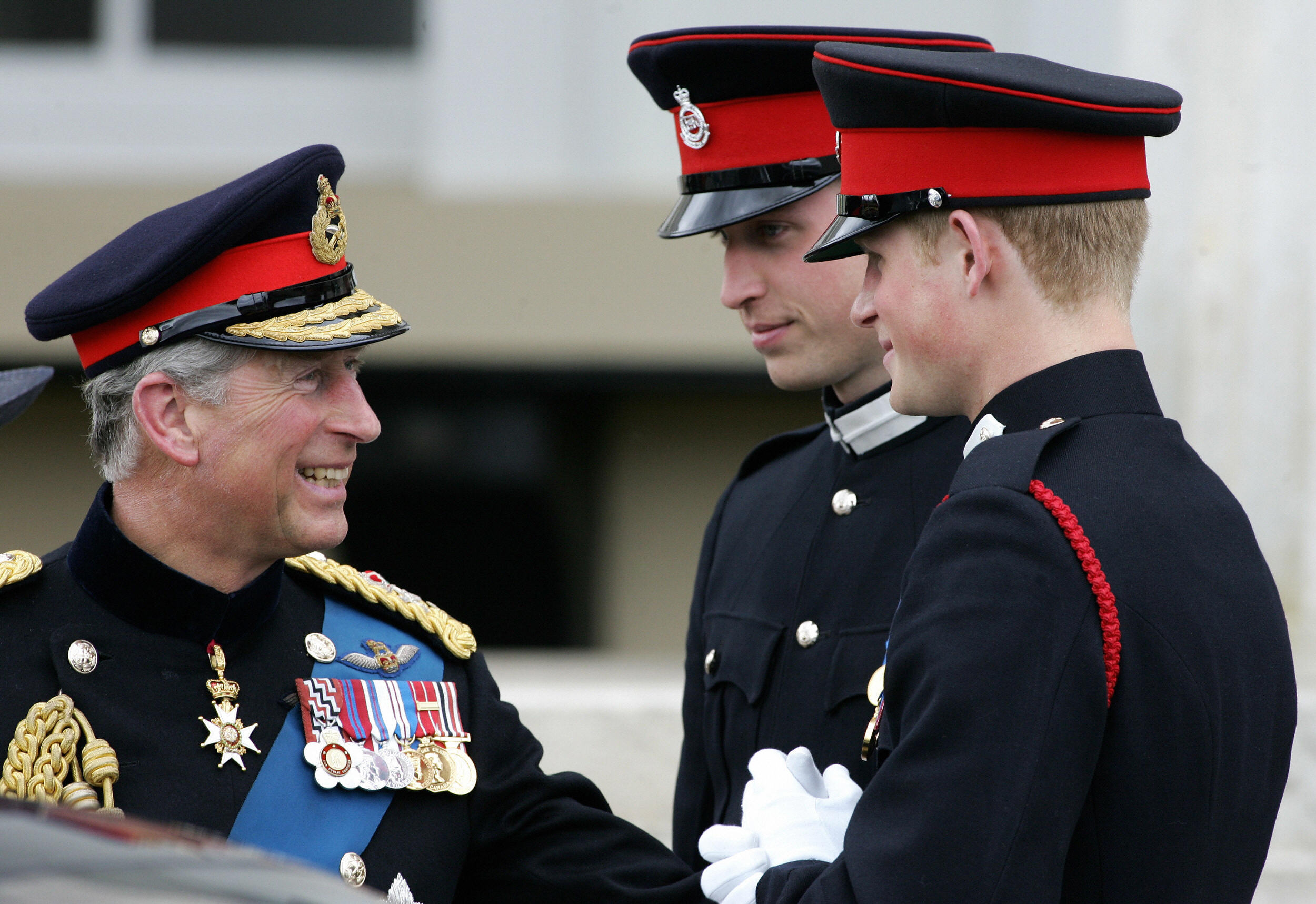 Le prince Charles (à gauche) s'entretient avec ses deux fils, les princes William (à droite) et Harry (à gauche), après avoir assisté à la parade du souverain à l'Académie militaire royale de Sandhurst, dans le sud de l'Angleterre, le 12 avril 2006. | Source : Getty Images