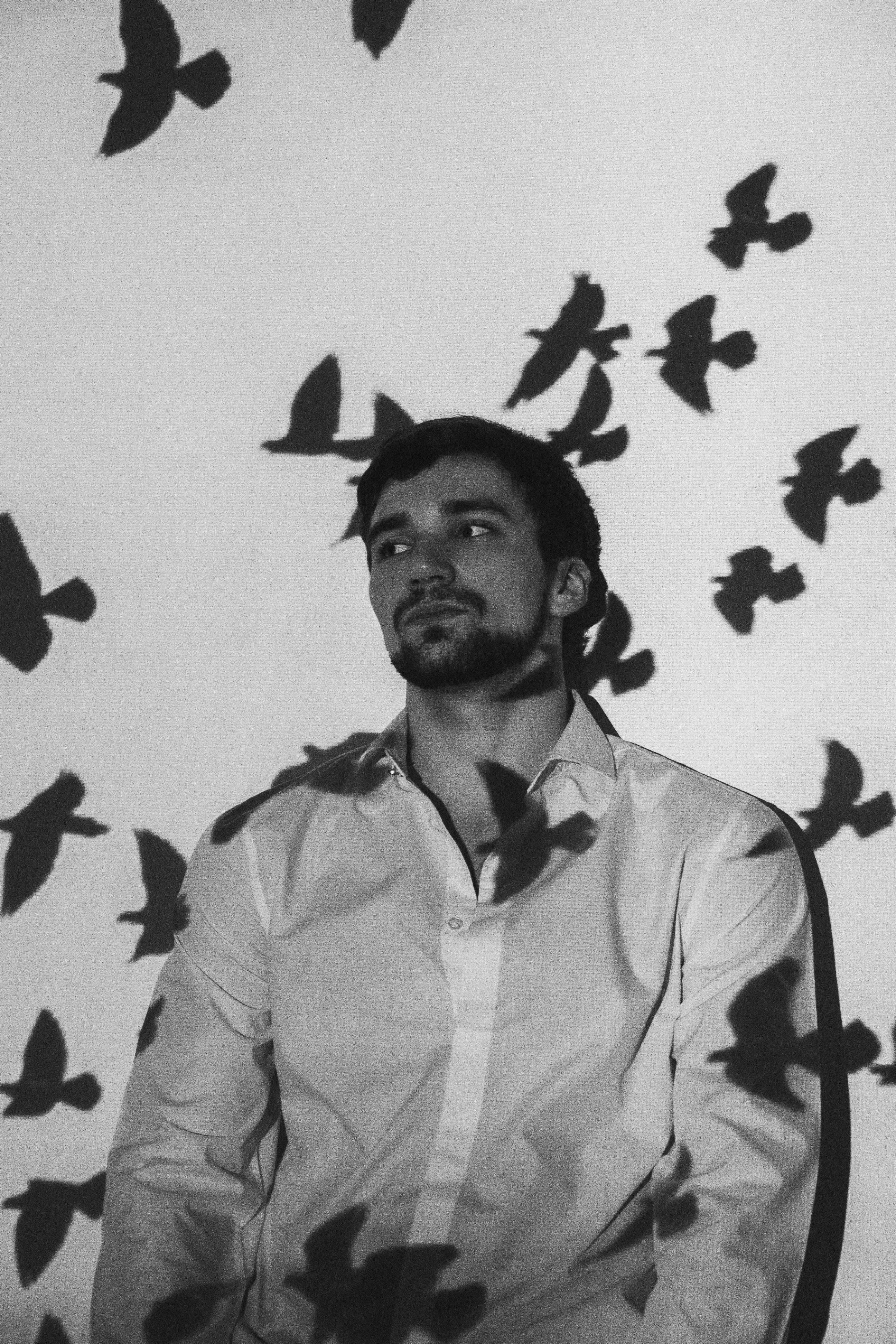 Homme pensif près d'un mur avec des ombres d'oiseaux | Source : Pexels