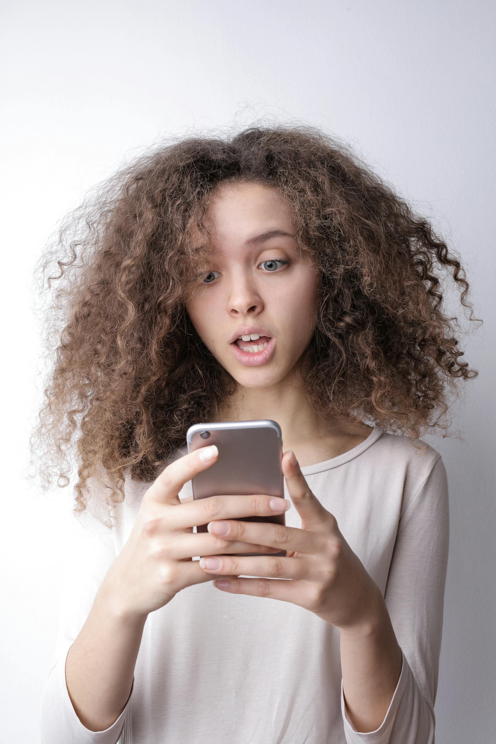 Une femme surprise vérifiant ses messages sur son téléphone | Source : Pexels