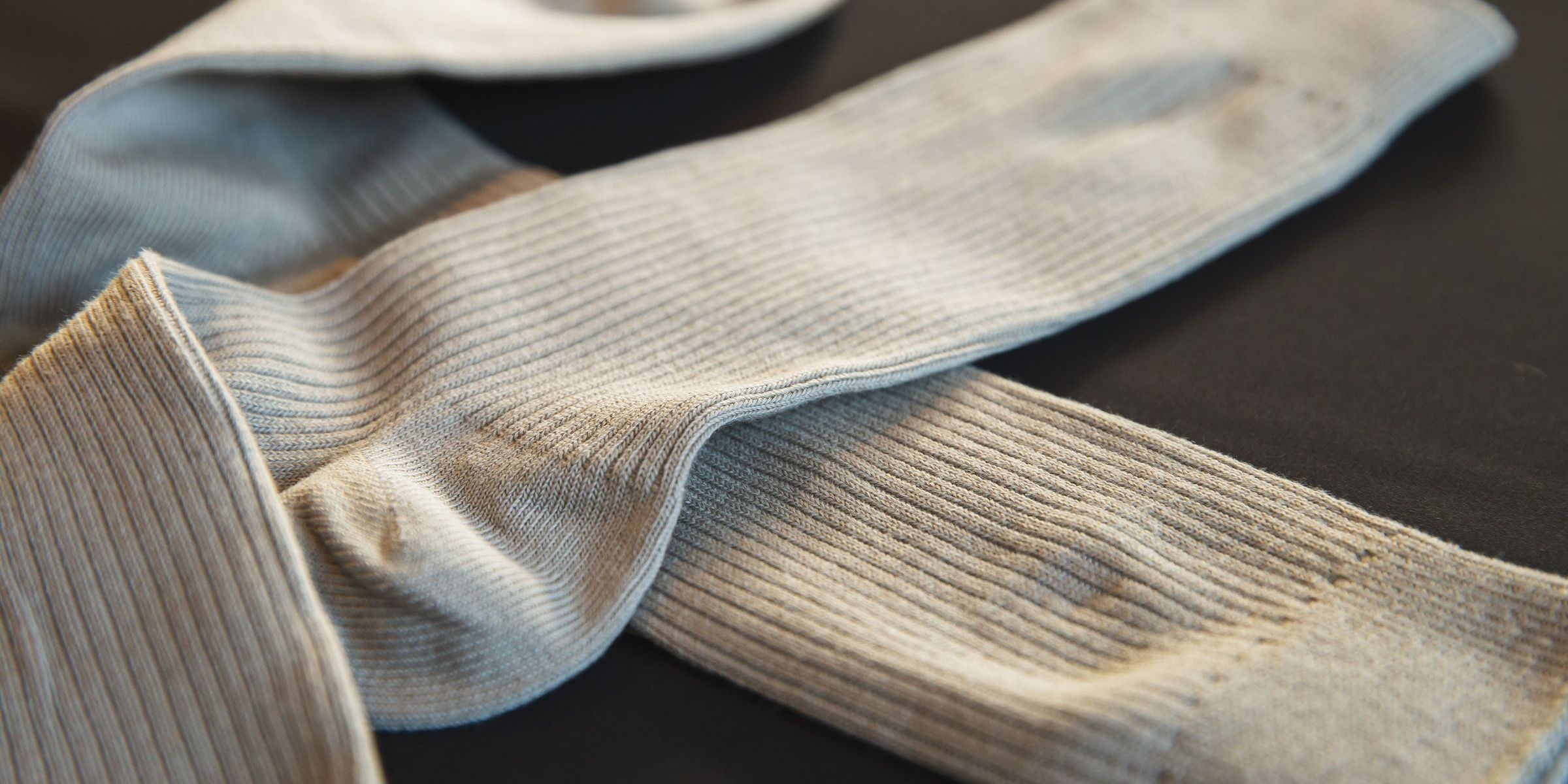 Gros plan sur une paire de chaussettes côtelées gris clair posées sur une surface sombre | Source : Pexels