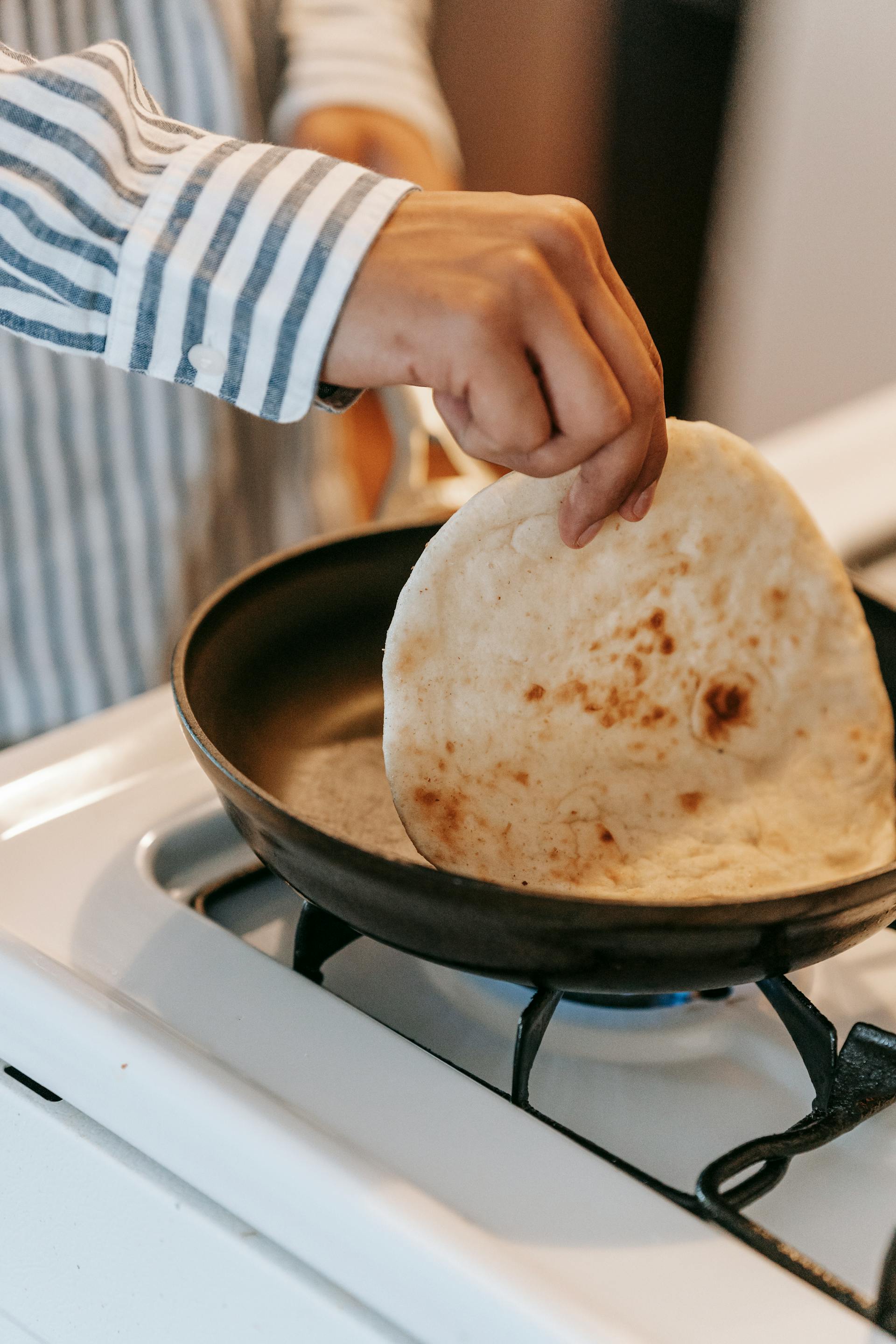 Un homme préparant des pains plats cuits à la poêle dans la cuisine | Source : Pexels