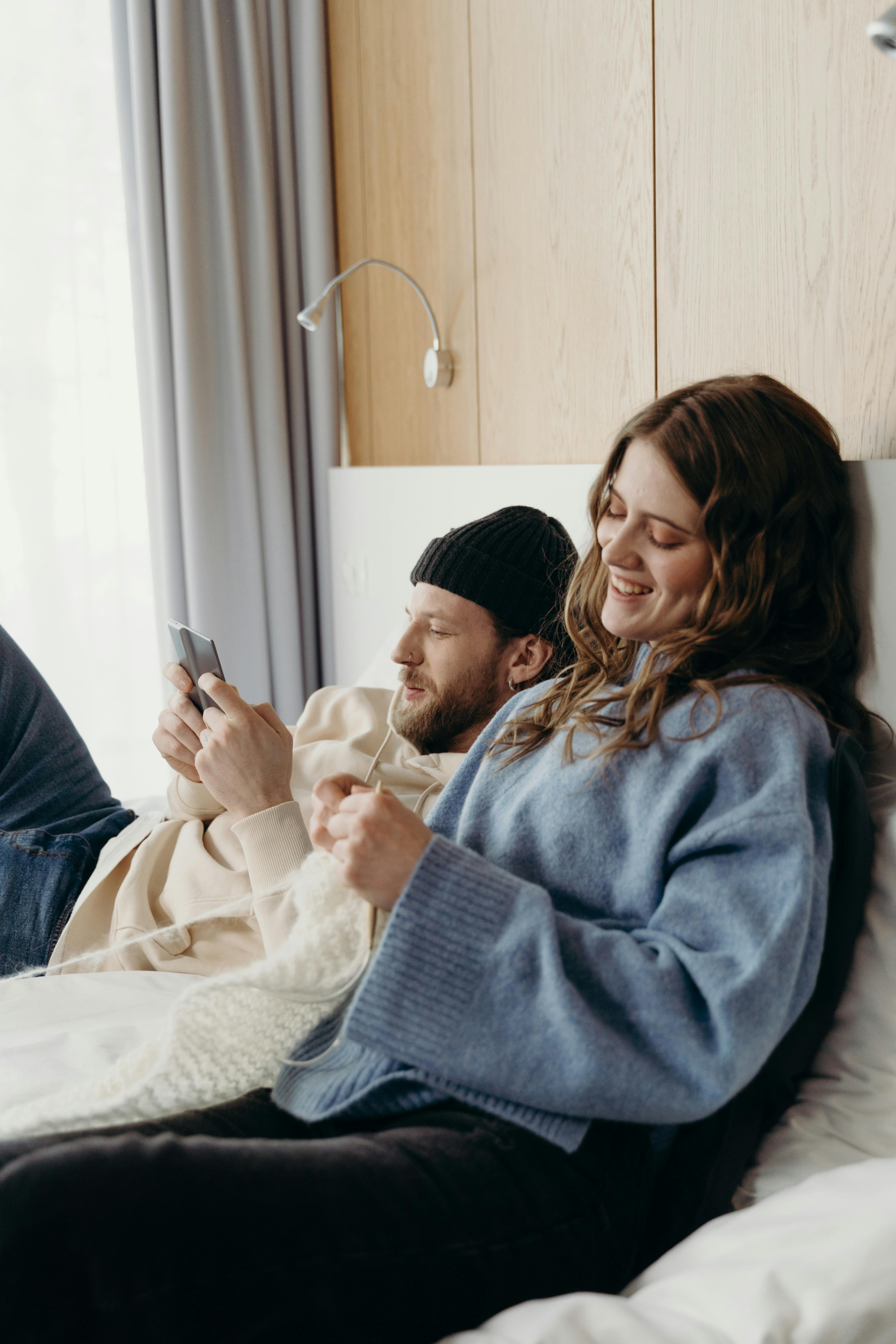 Une femme heureuse qui tricote pendant que son mari utilise son téléphone | Source : Pexels