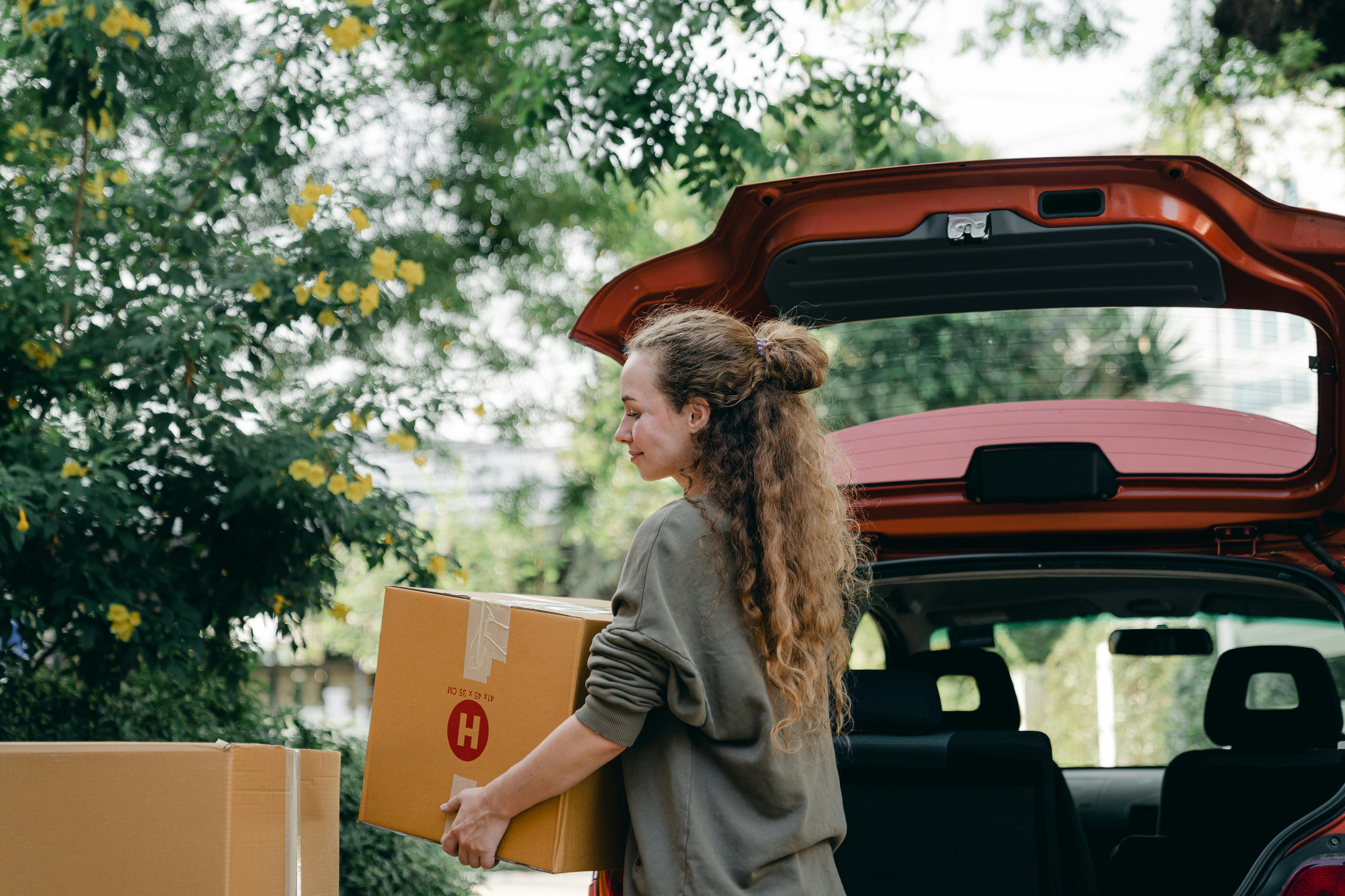 Une femme heureuse qui charge des cartons dans sa voiture | Source : Pexels