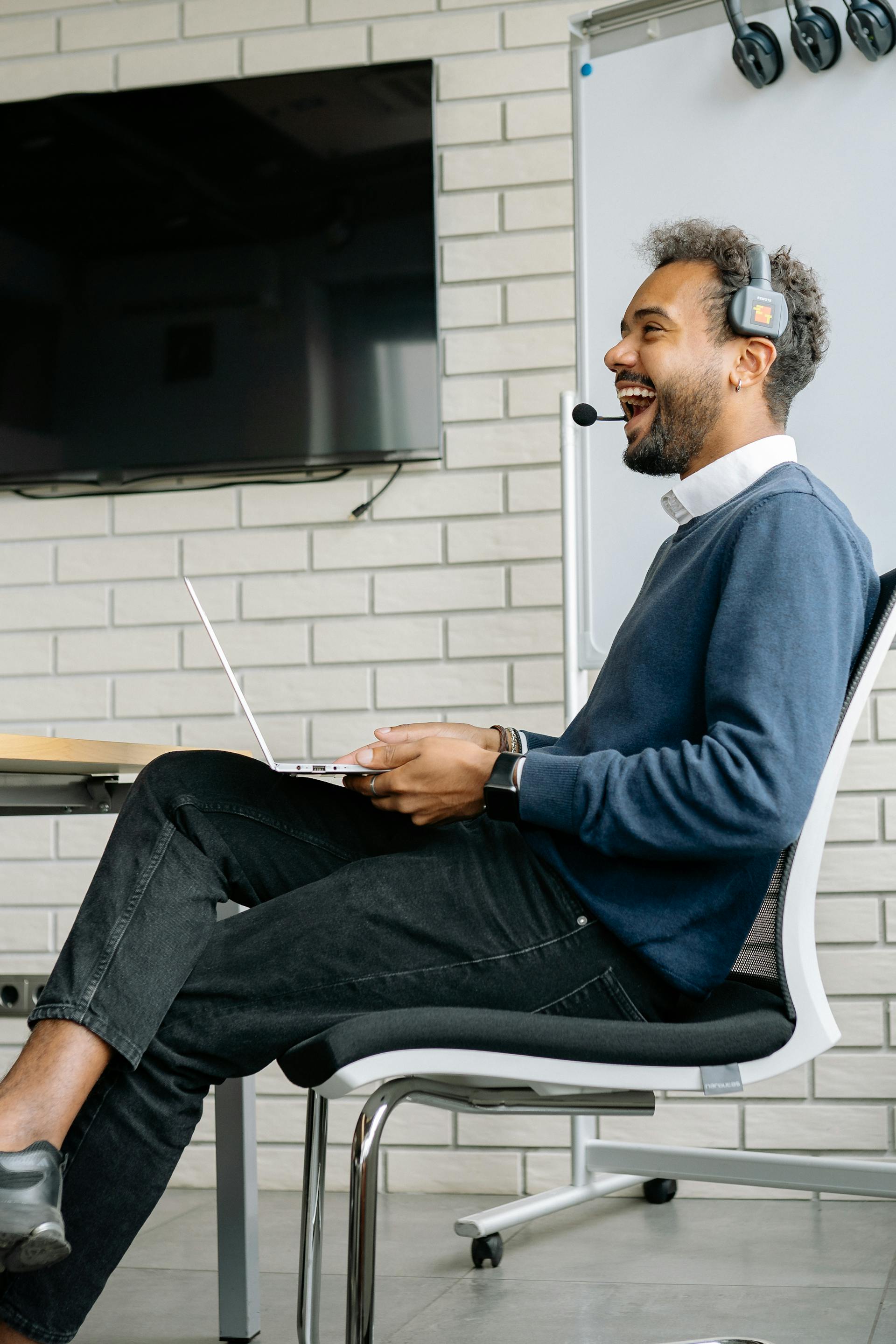 Un homme rit alors qu'il est assis sur une chaise dans un bureau | Source : Pexels