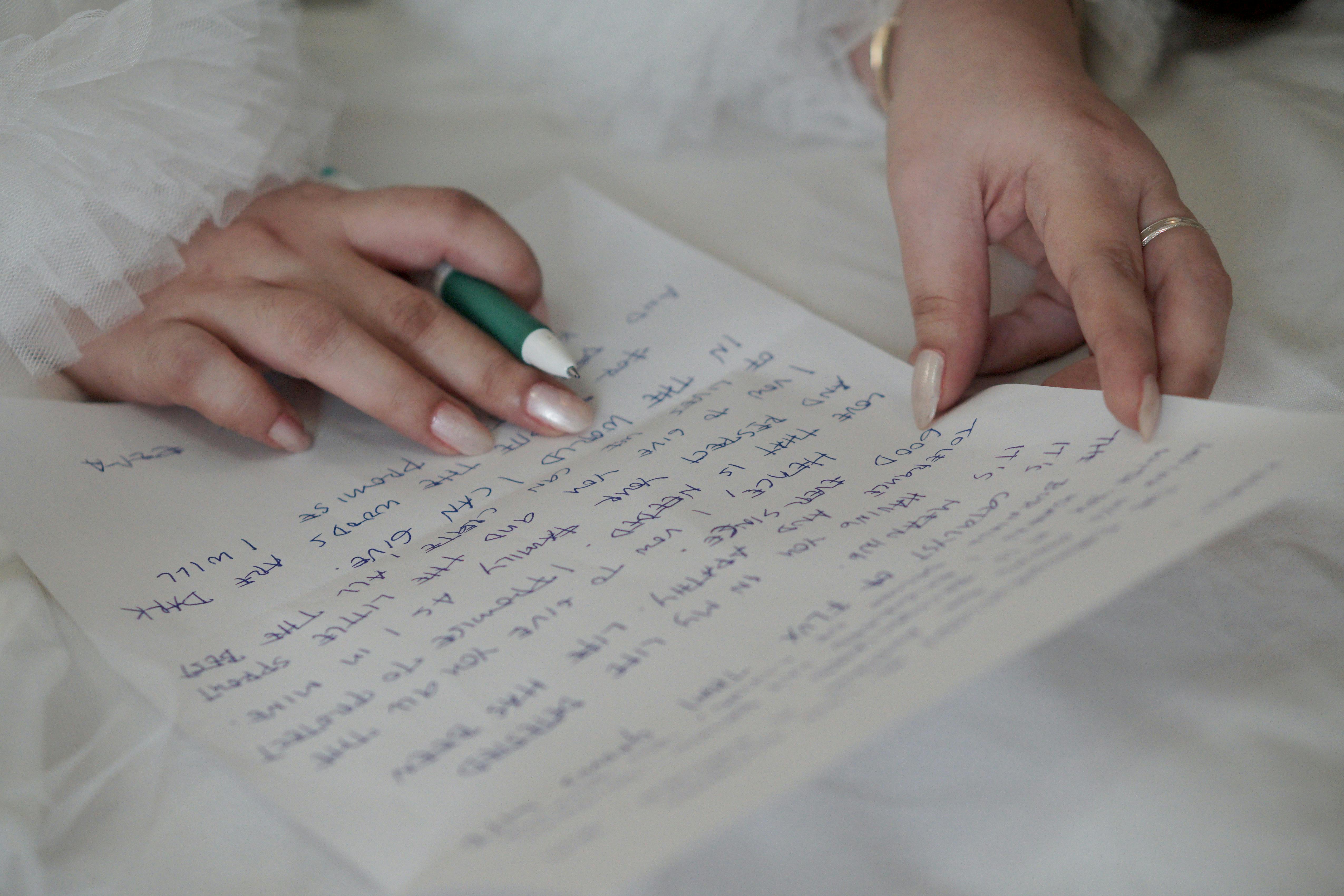 Les mains d'une femme tenant un stylo pendant qu'elle écrit une lettre | Source : Pexels