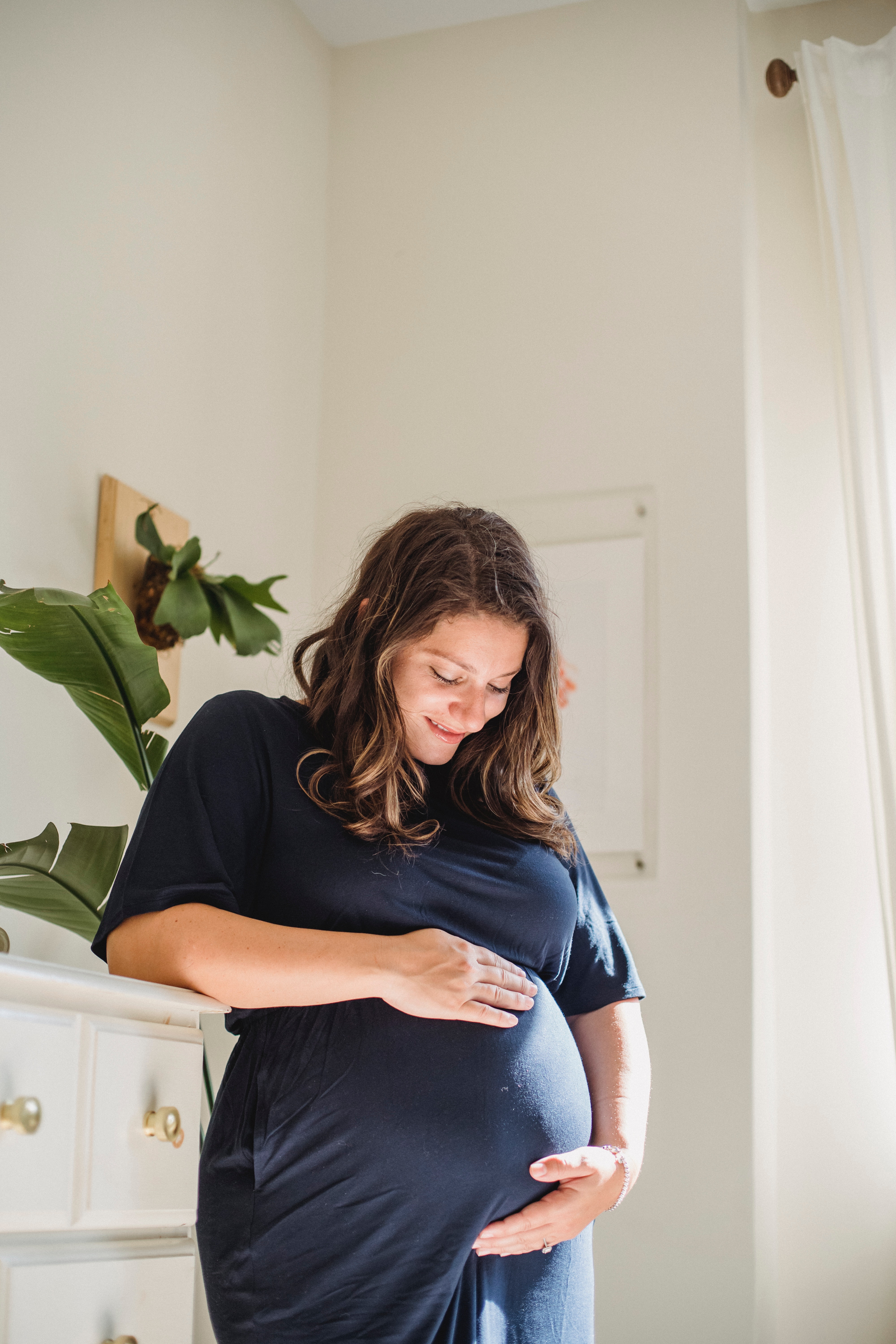 Une femme qui sourit à son ventre de femme enceinte | Source : Pexels