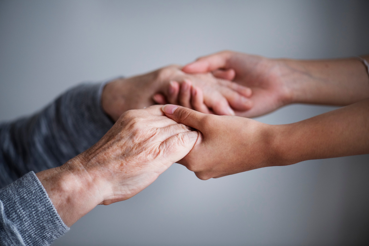 Gros plan sur une jeune femme tenant les mains d'une dame plus âgée | Source : Freepik