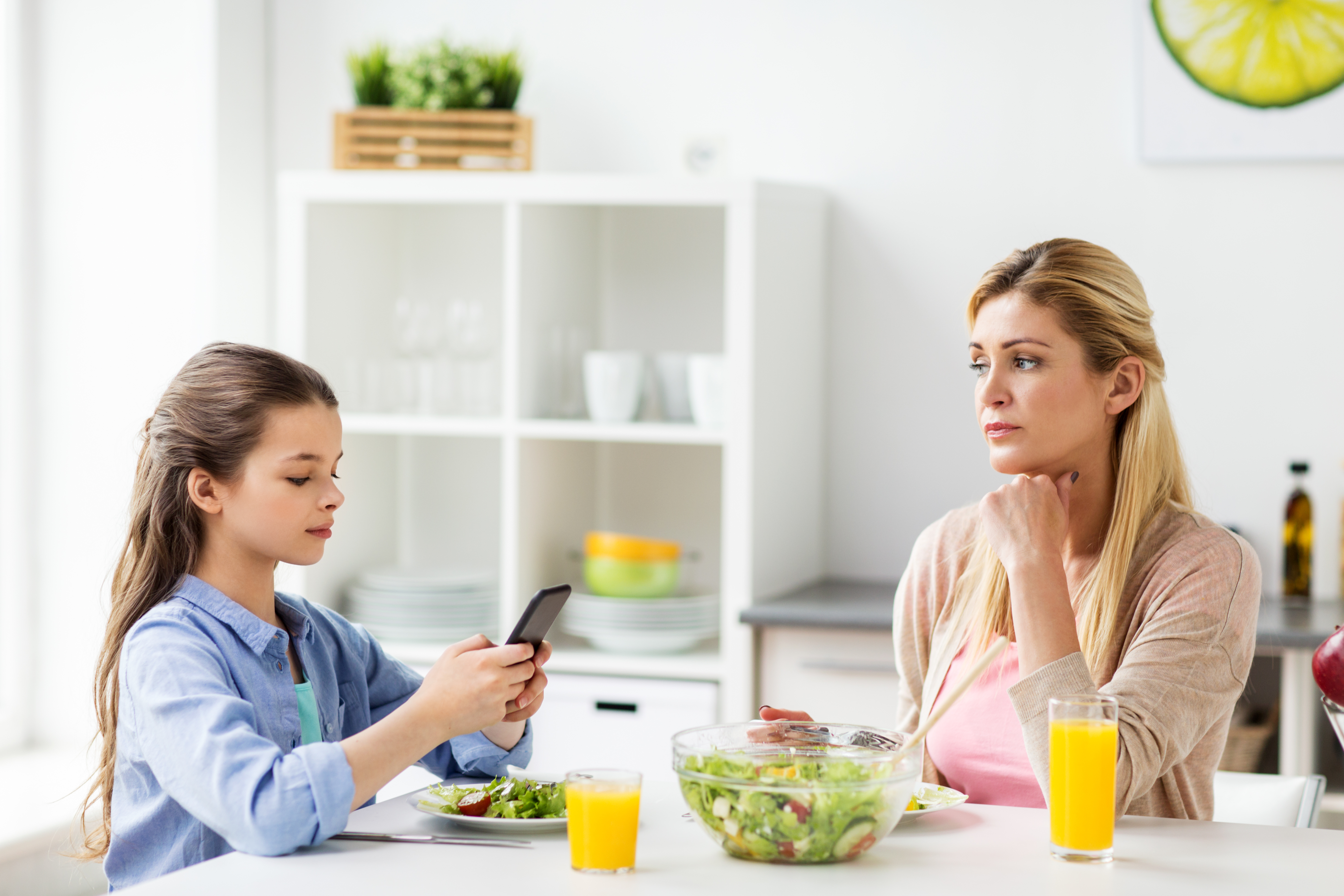 Une femme triste et une jeune fille à la table à manger | Source : Shutterstock
