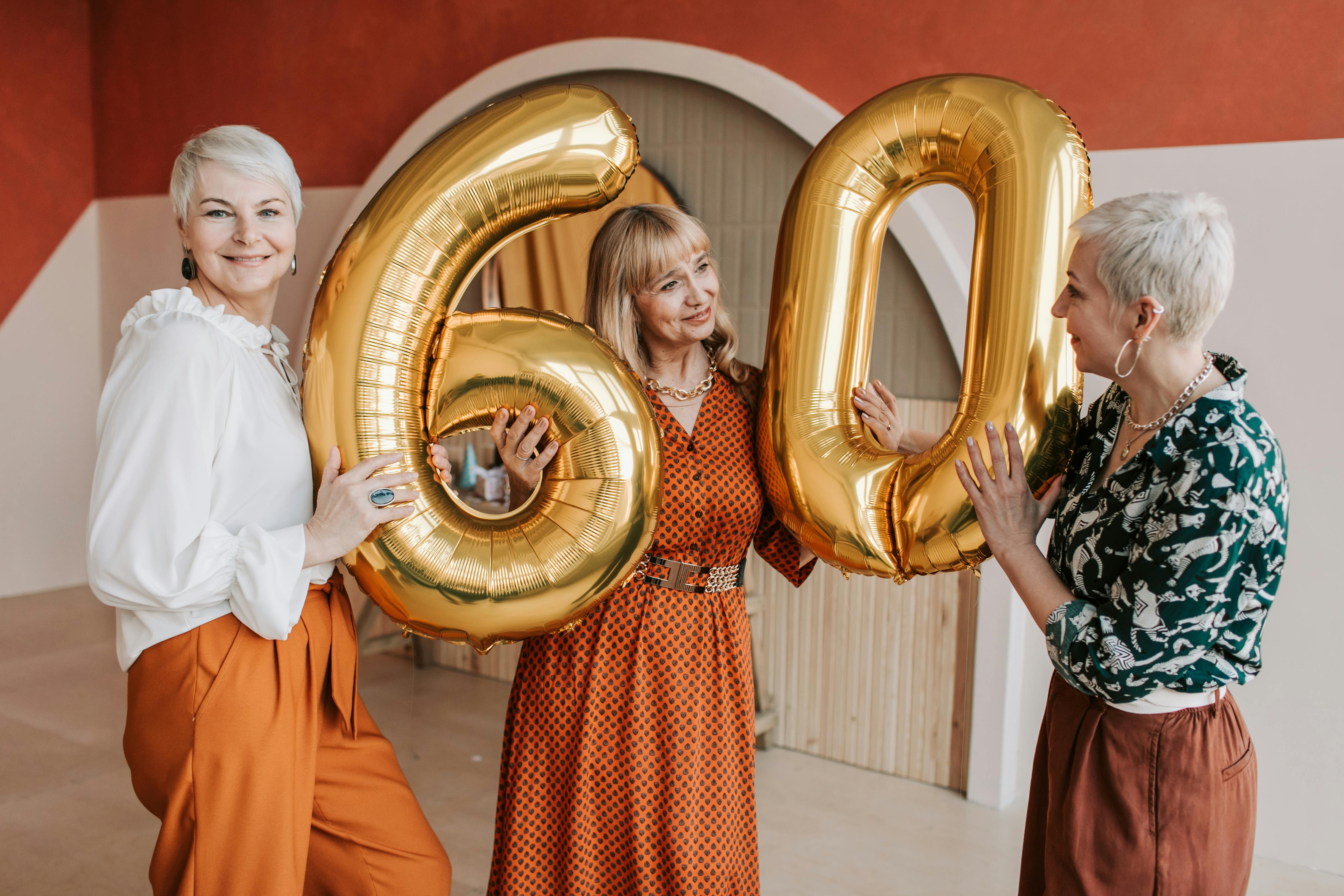 Trois femmes brandissent des ballons d'anniversaire sur lesquels est écrit le nombre "60" | Source : Pexels