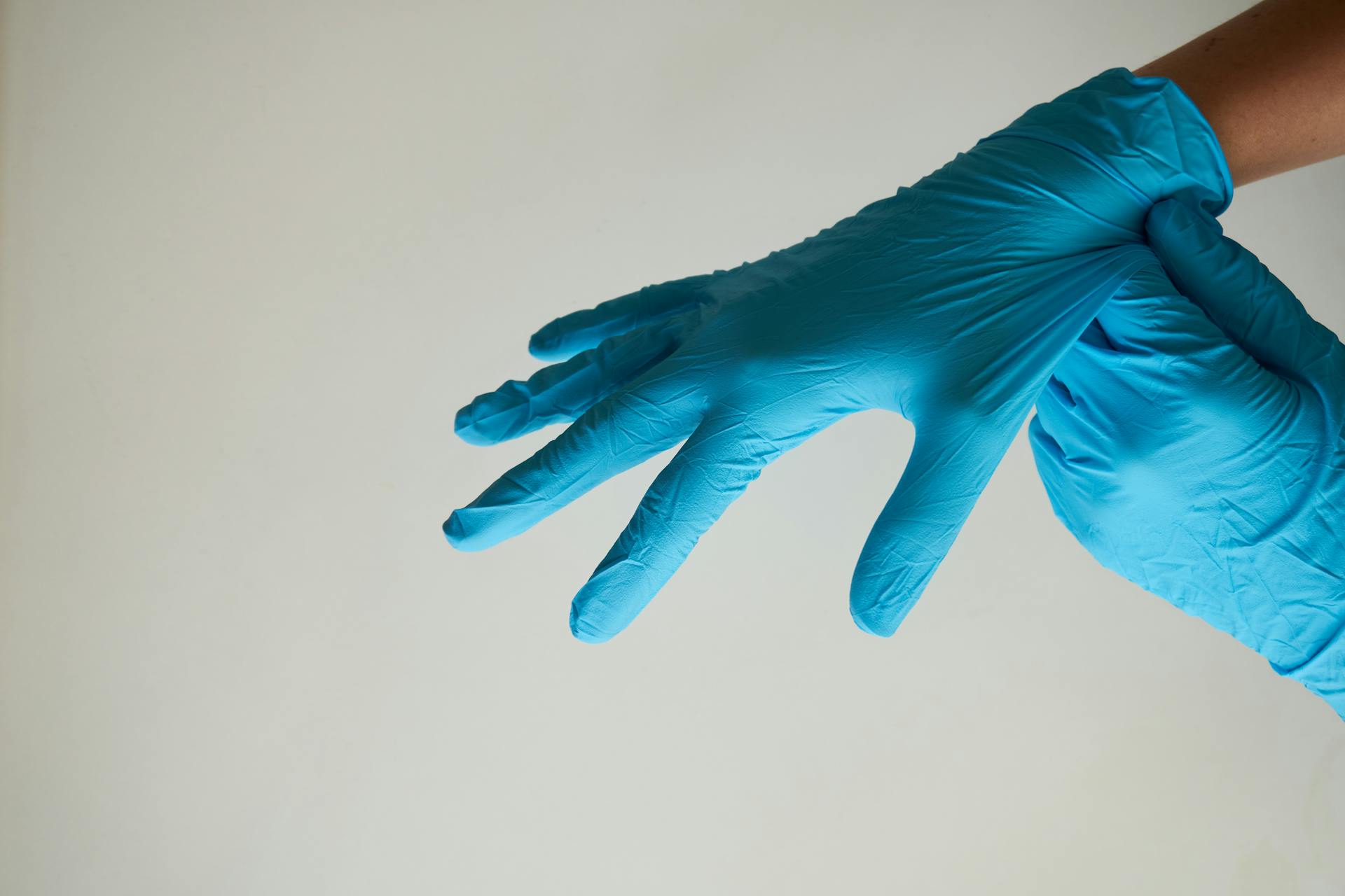 Une femme enfilant des gants en latex bleus | Source : Pexels