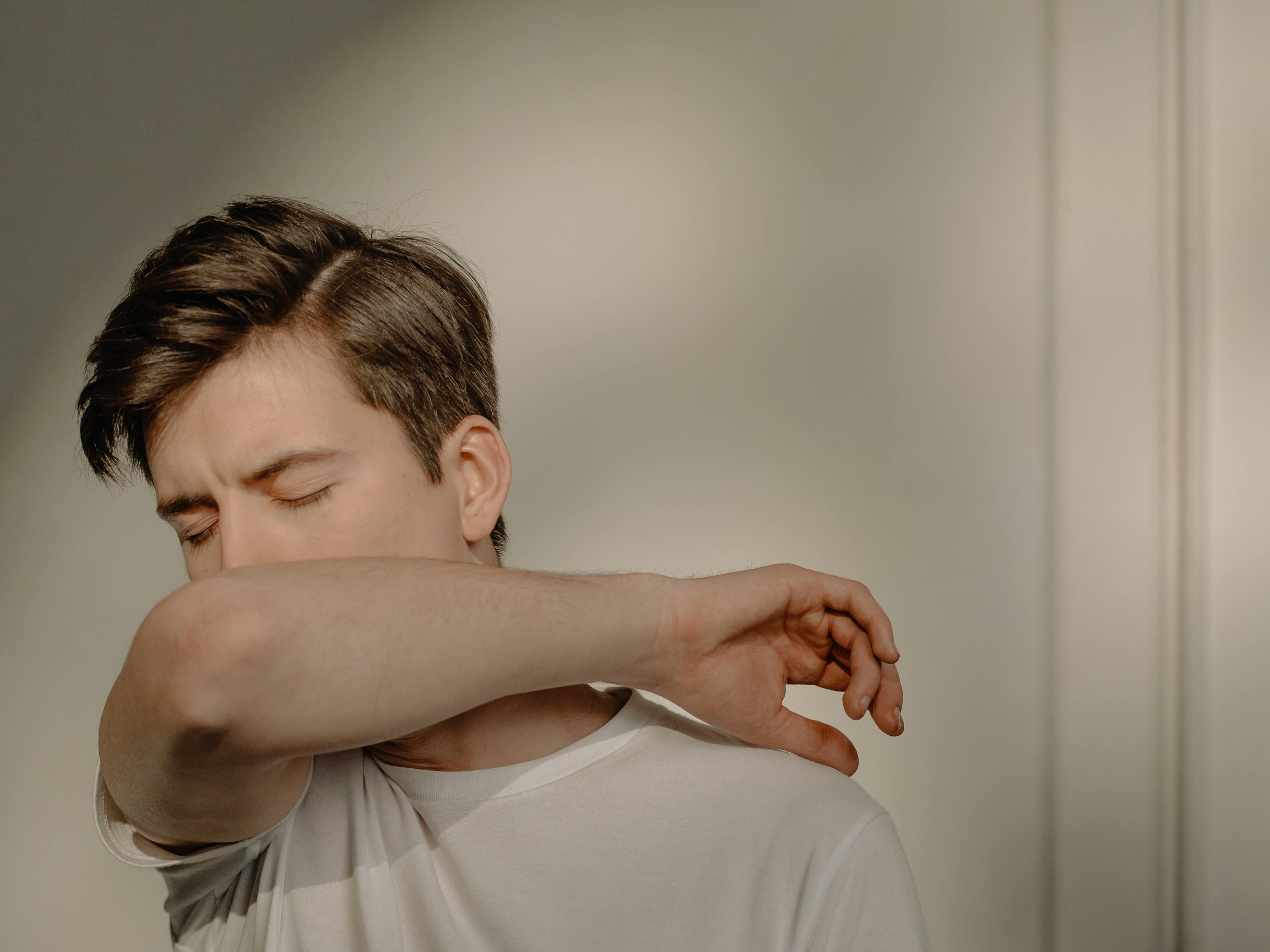 Un homme qui tousse dans son bras | Source : Pexels