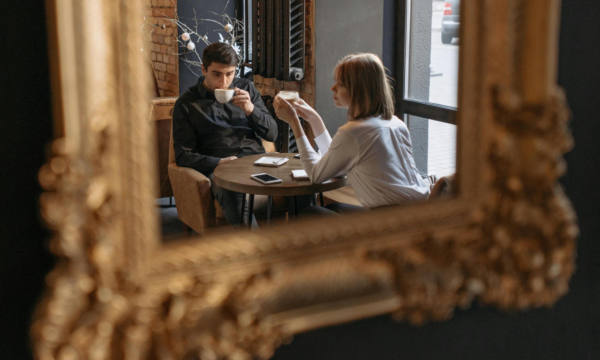 Un homme et une femme vus reflétés dans le miroir d'un café | Source : Pexels