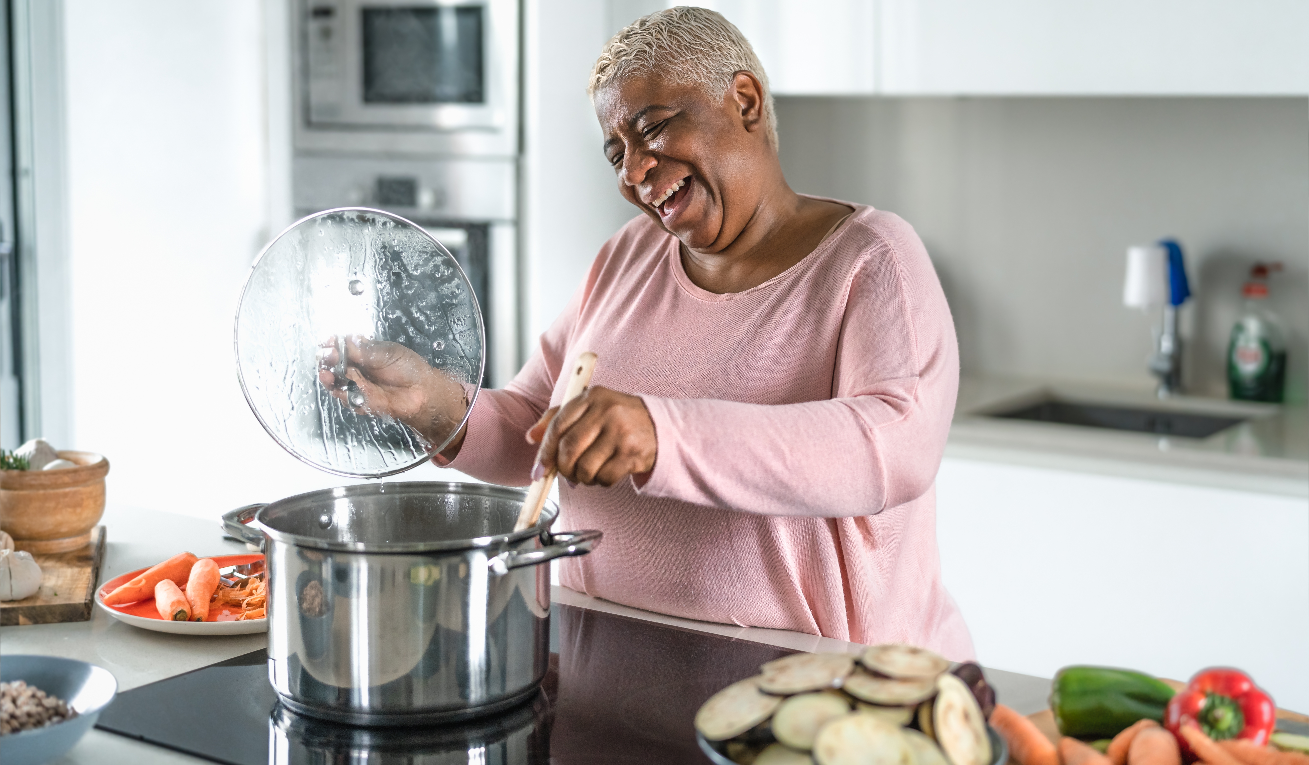 Femme âgée souriant en cuisinant | Source : Shutterstock