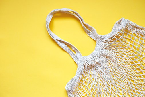 Sac tricoté de corde de coton beige sur le fond jaune. | Photo : Getty Images