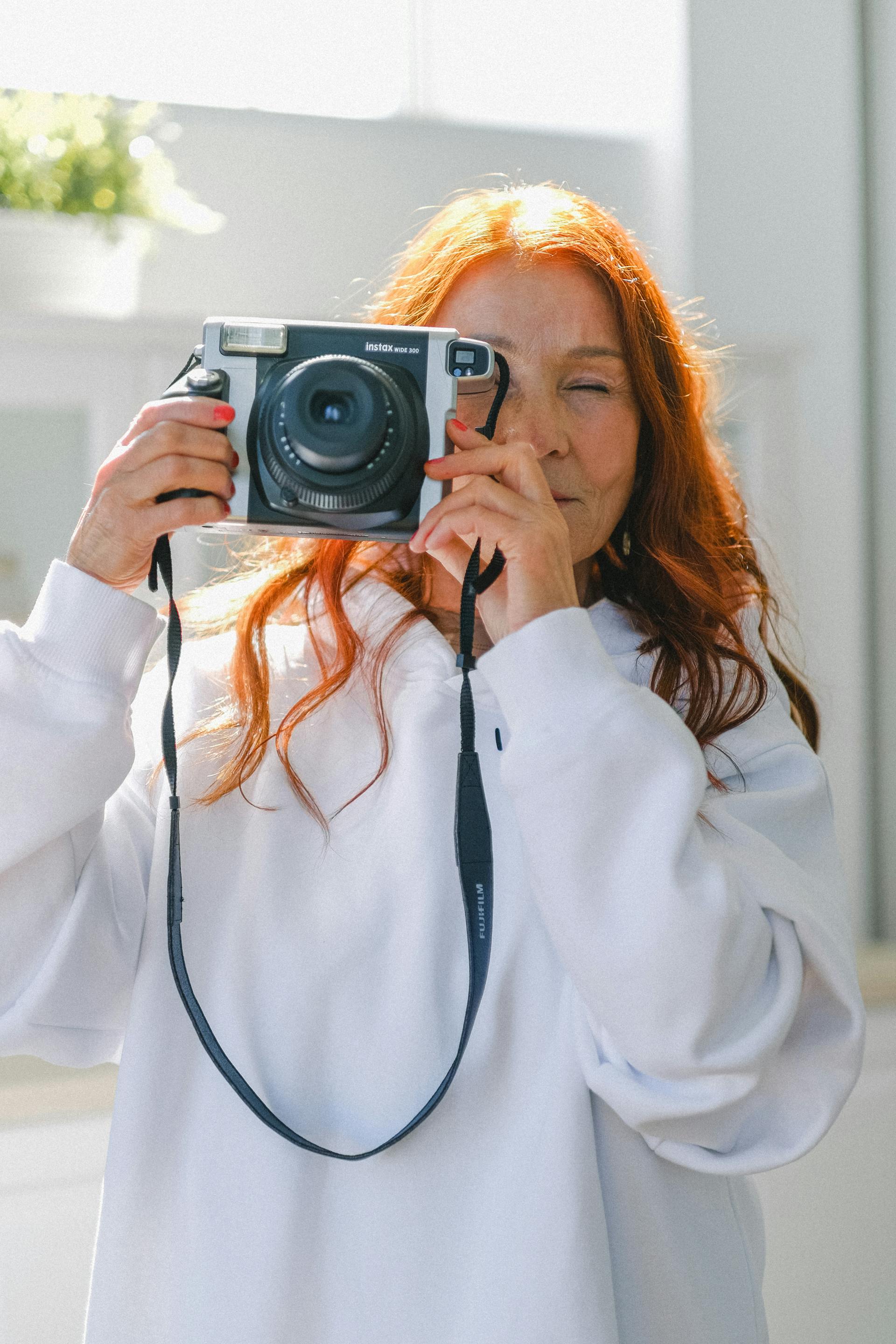 Une femme senior aux cheveux roux avec un appareil photo vintage | Source : Pexels