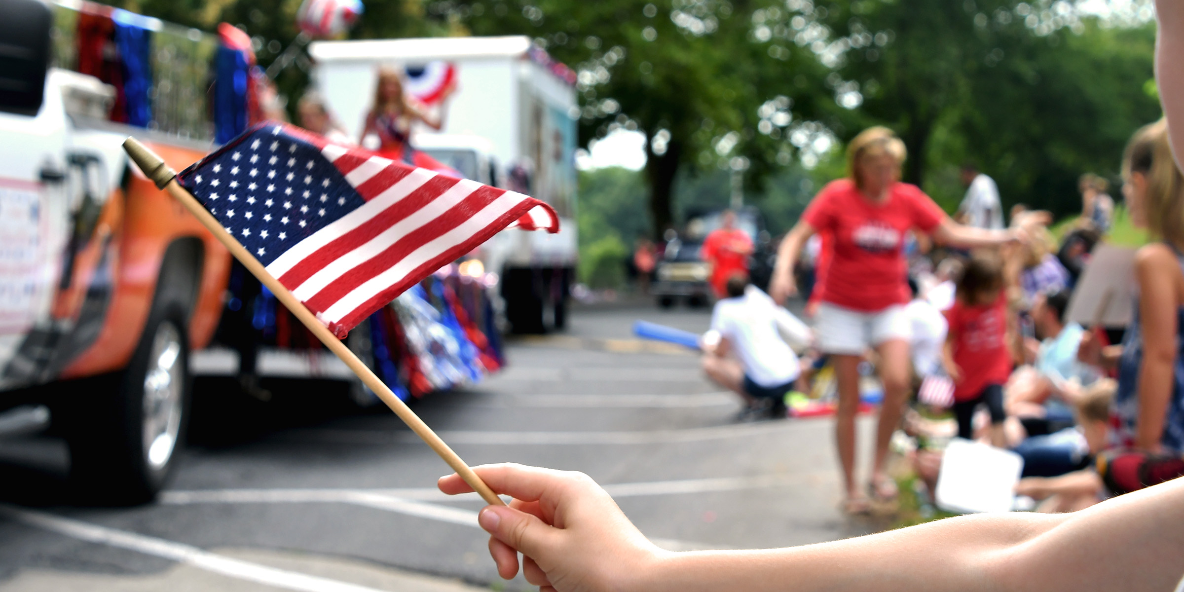 Une personne agitant un drapeau américain lors d'un défilé animé du 4 juillet | Source : Shutterstock