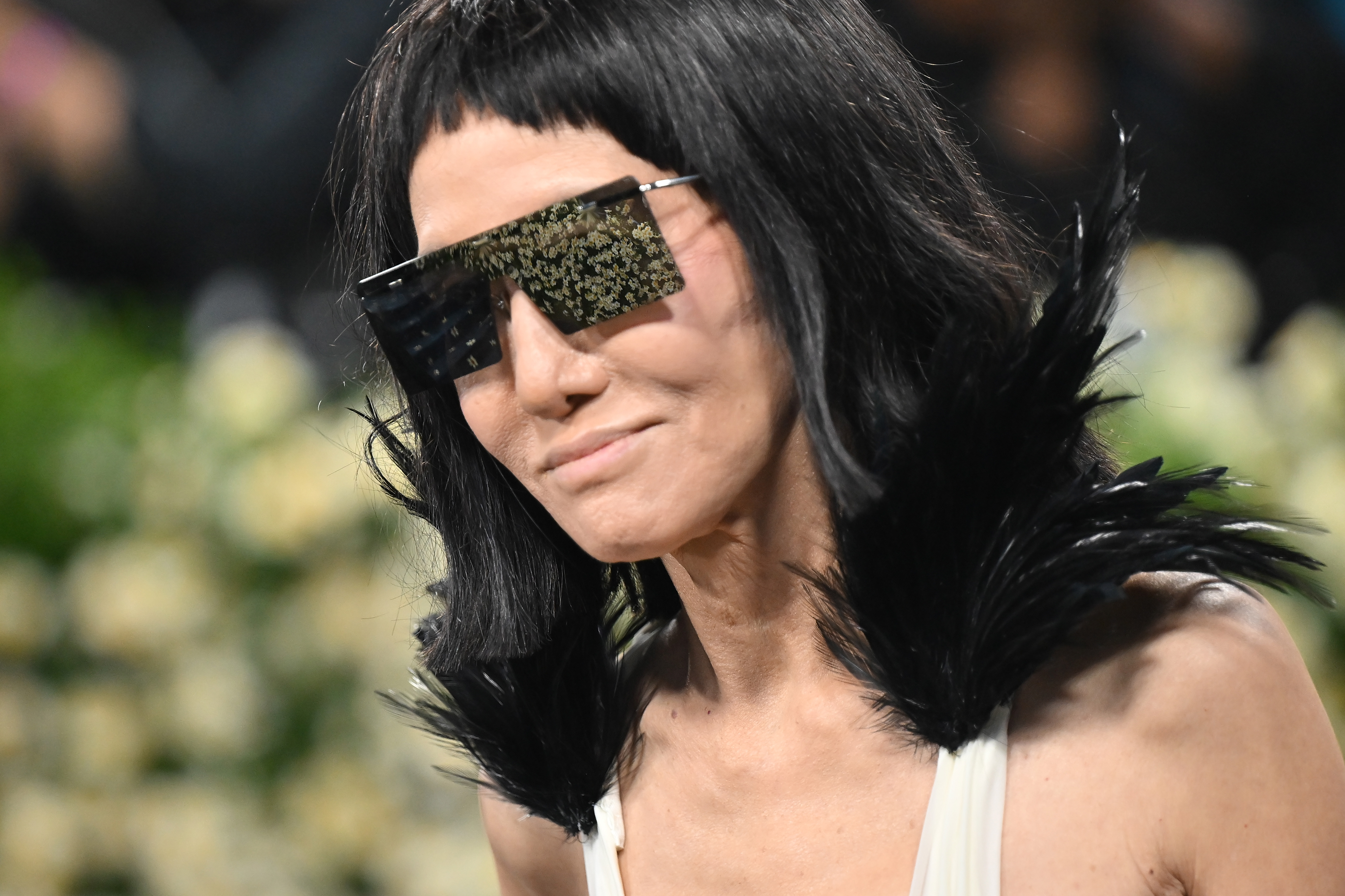 Vera Wang arbore de grandes lunettes de soleil réfléchissantes et un col noir ébène en plumes à son arrivée, offrant un aperçu des détails audacieux de sa tenue sur mesure.