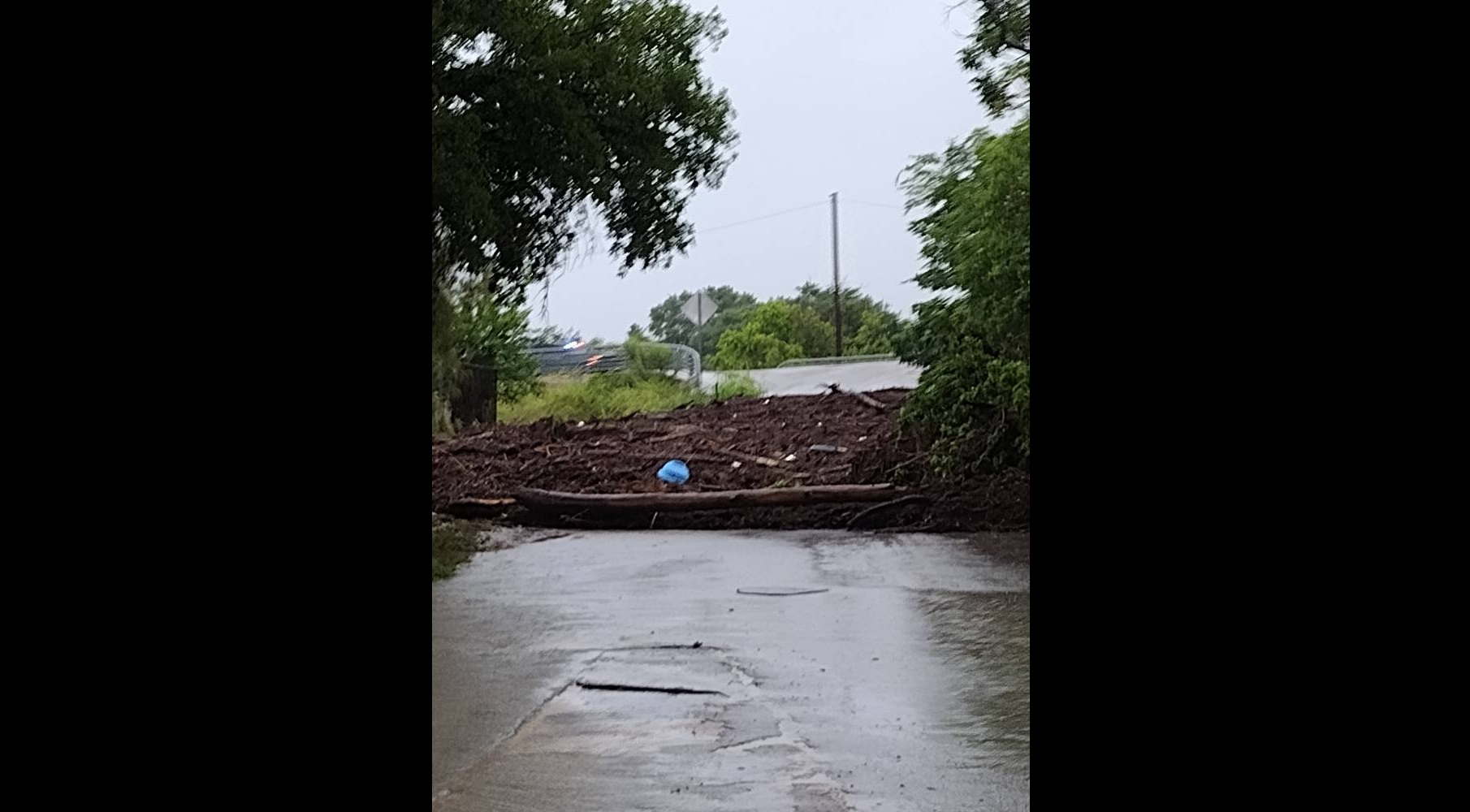 Débris déposés par les eaux de crue bloquant une route pavée dans le comté de Kerr, au Texas, d'après un post Facebook daté du 5 juillet 2025. | Source : facebook.com/jennyandmason