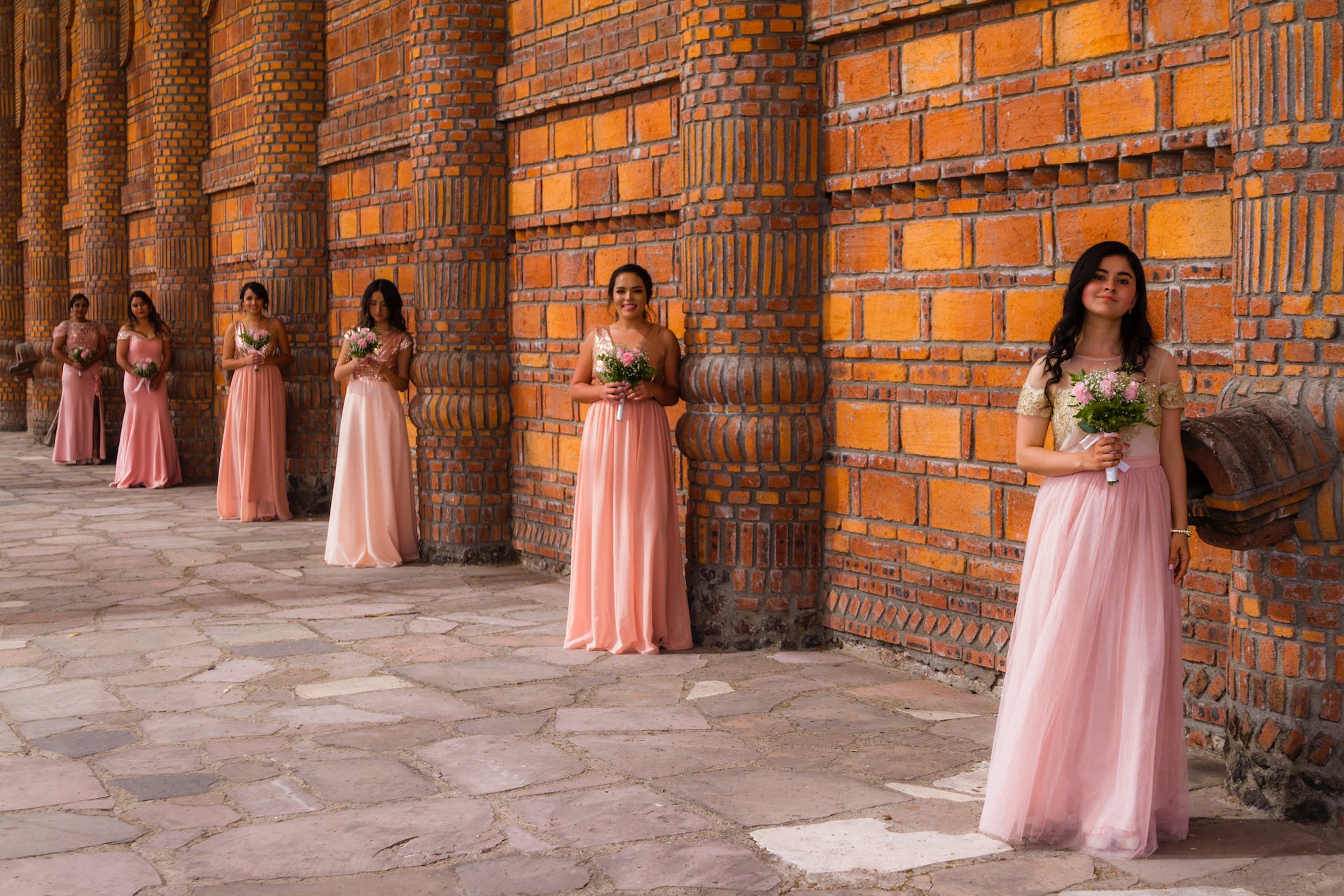 Mujeres con vestidos rosas sosteniendo flores | Fuente: Pexels