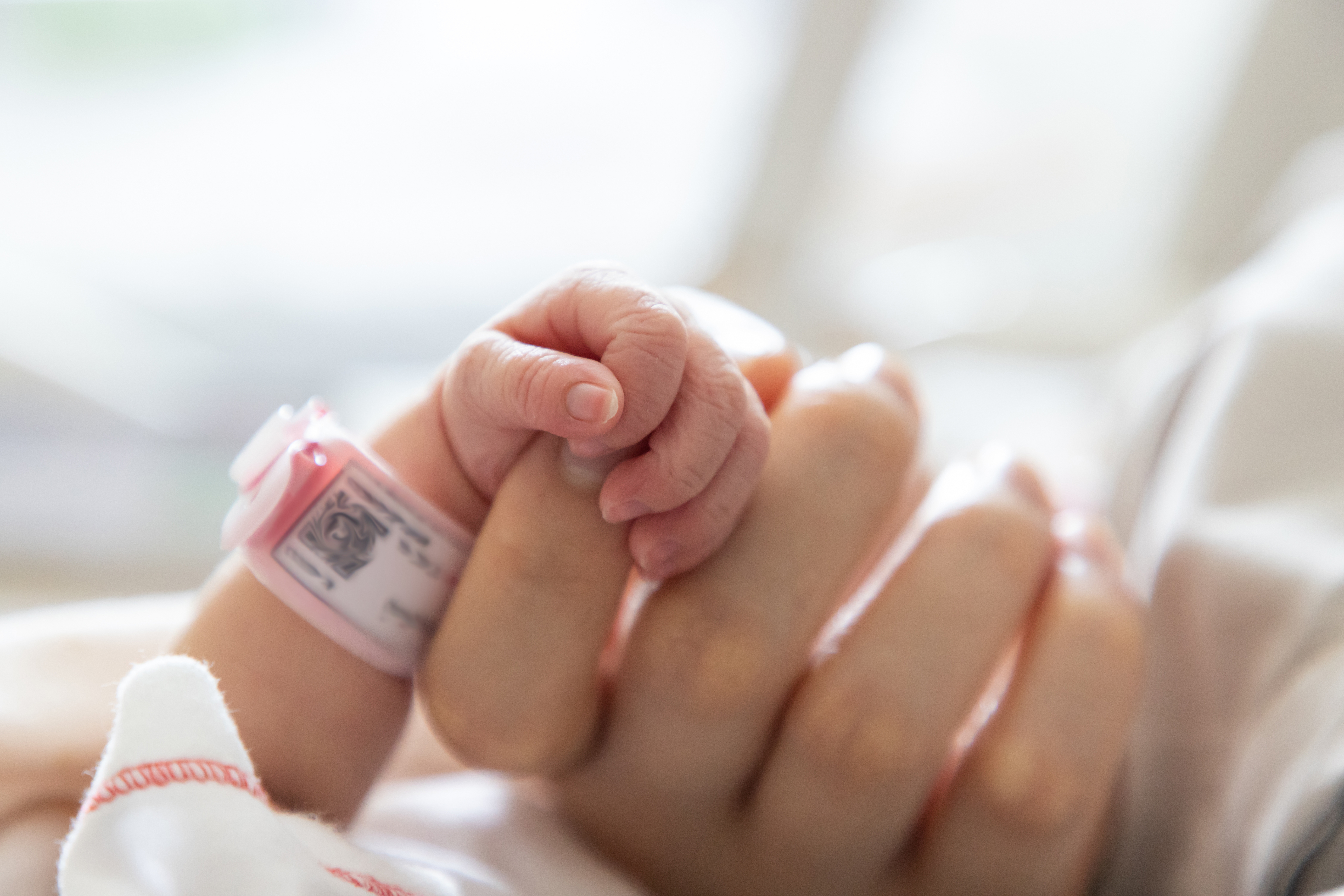 La main d'un bébé serrant le doigt d'une femme | Source : Shutterstock