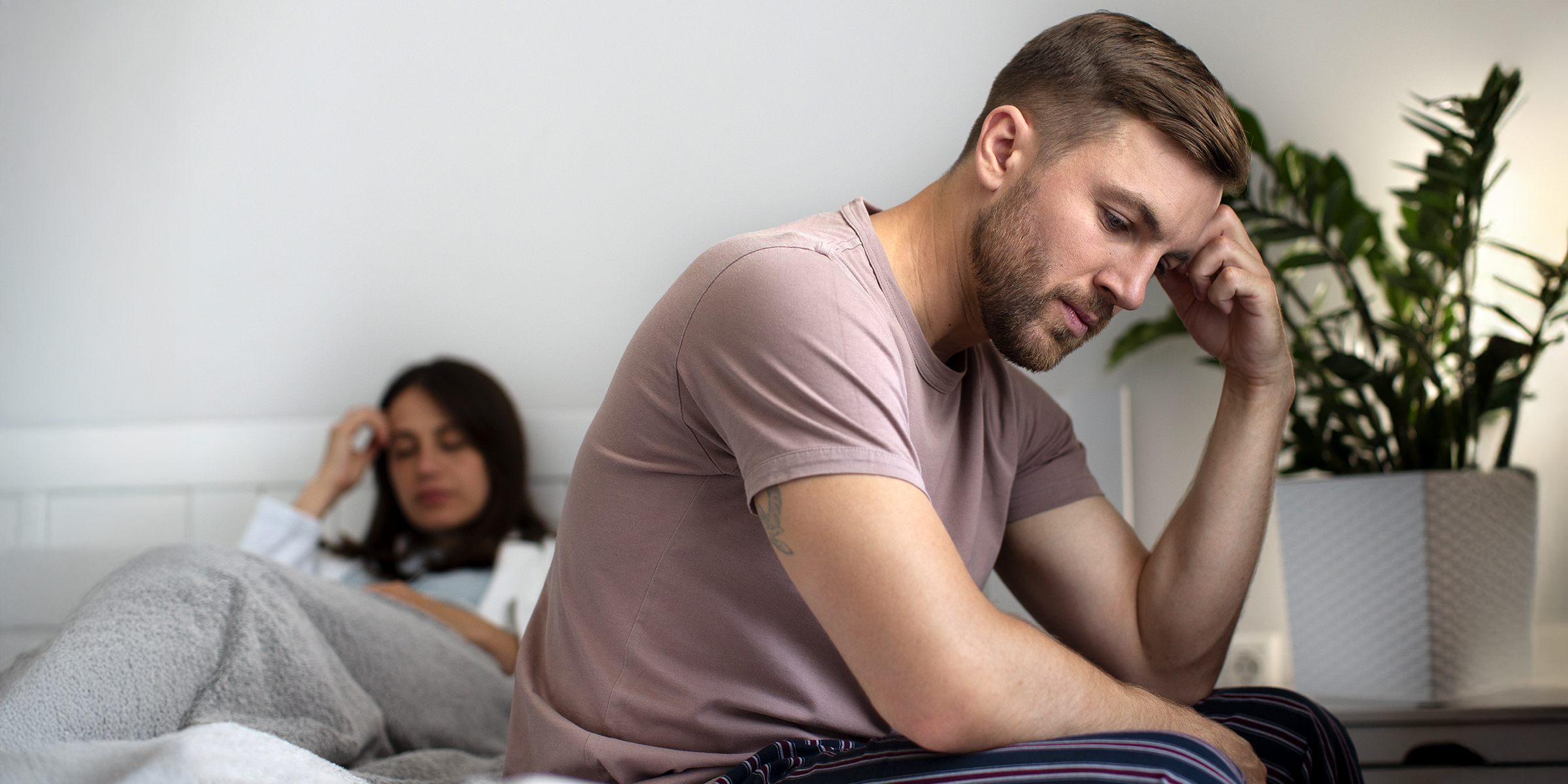 Un couple bouleversé assis sur un lit | Source : Freepik