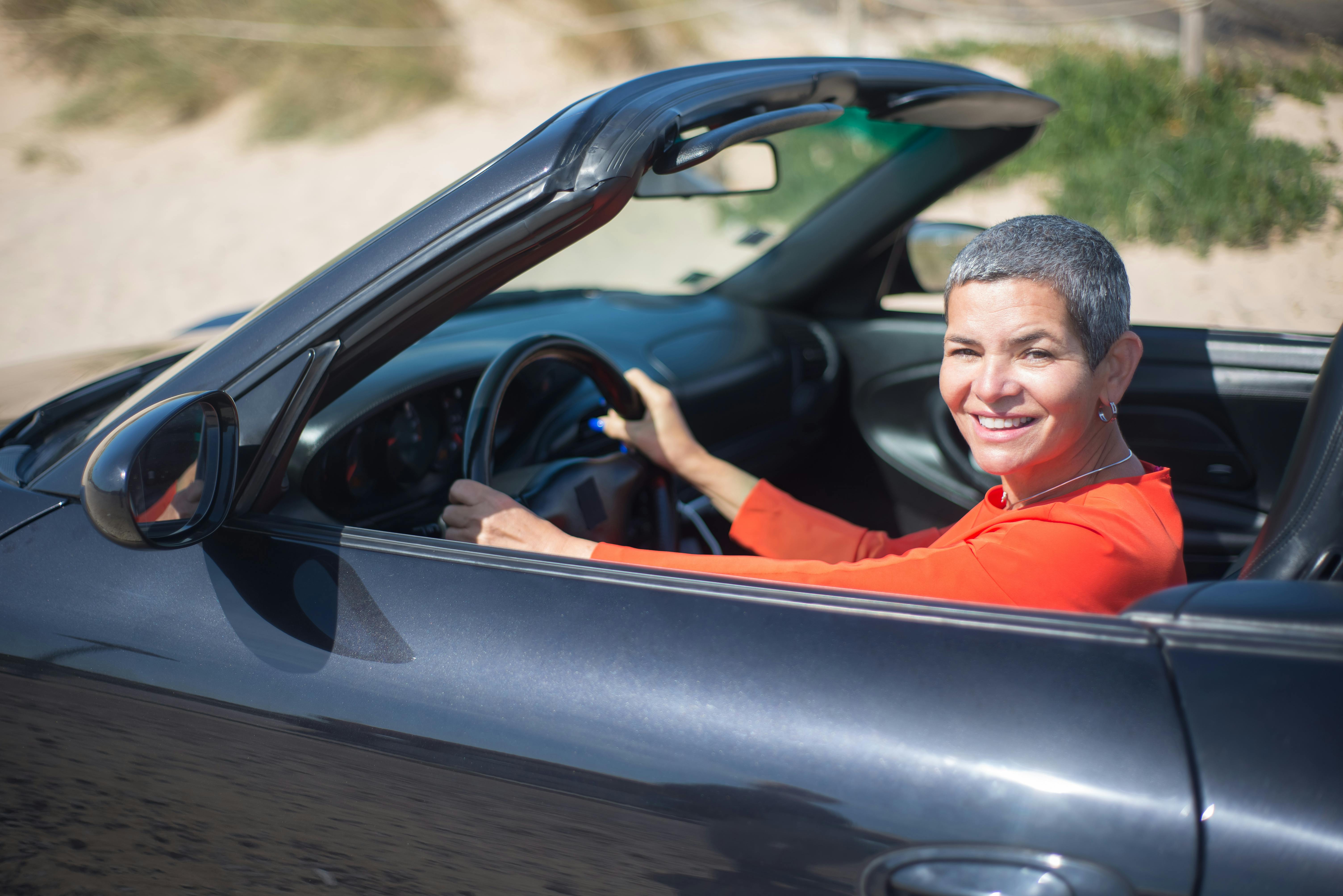 Une femme souriante au volant d'une voiture | Source : Pexels
