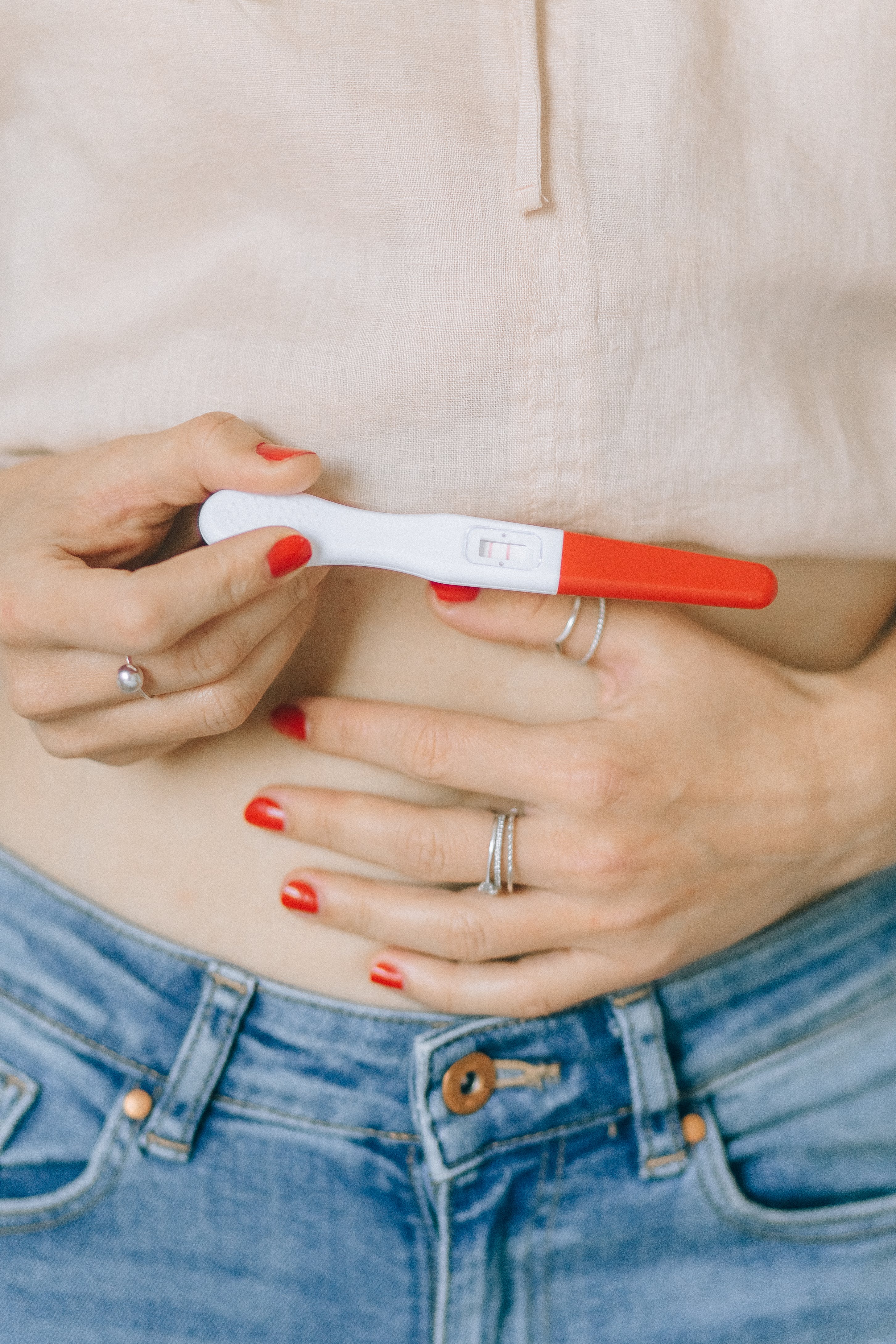 Une femme tenant son ventre et un test de grossesse | Source : Pexels