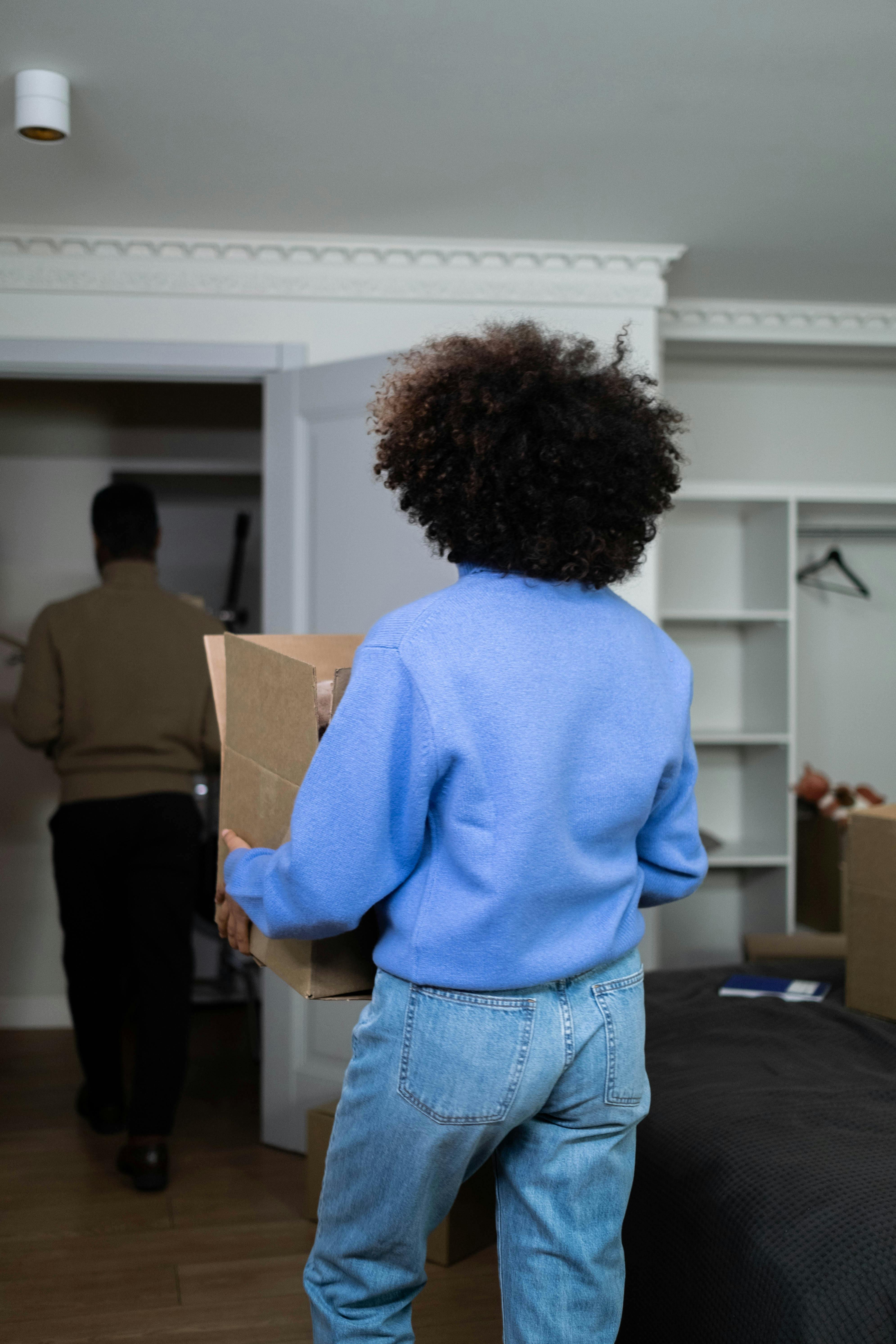 Un couple qui sort de la maison avec des cartons | Source : Pexels