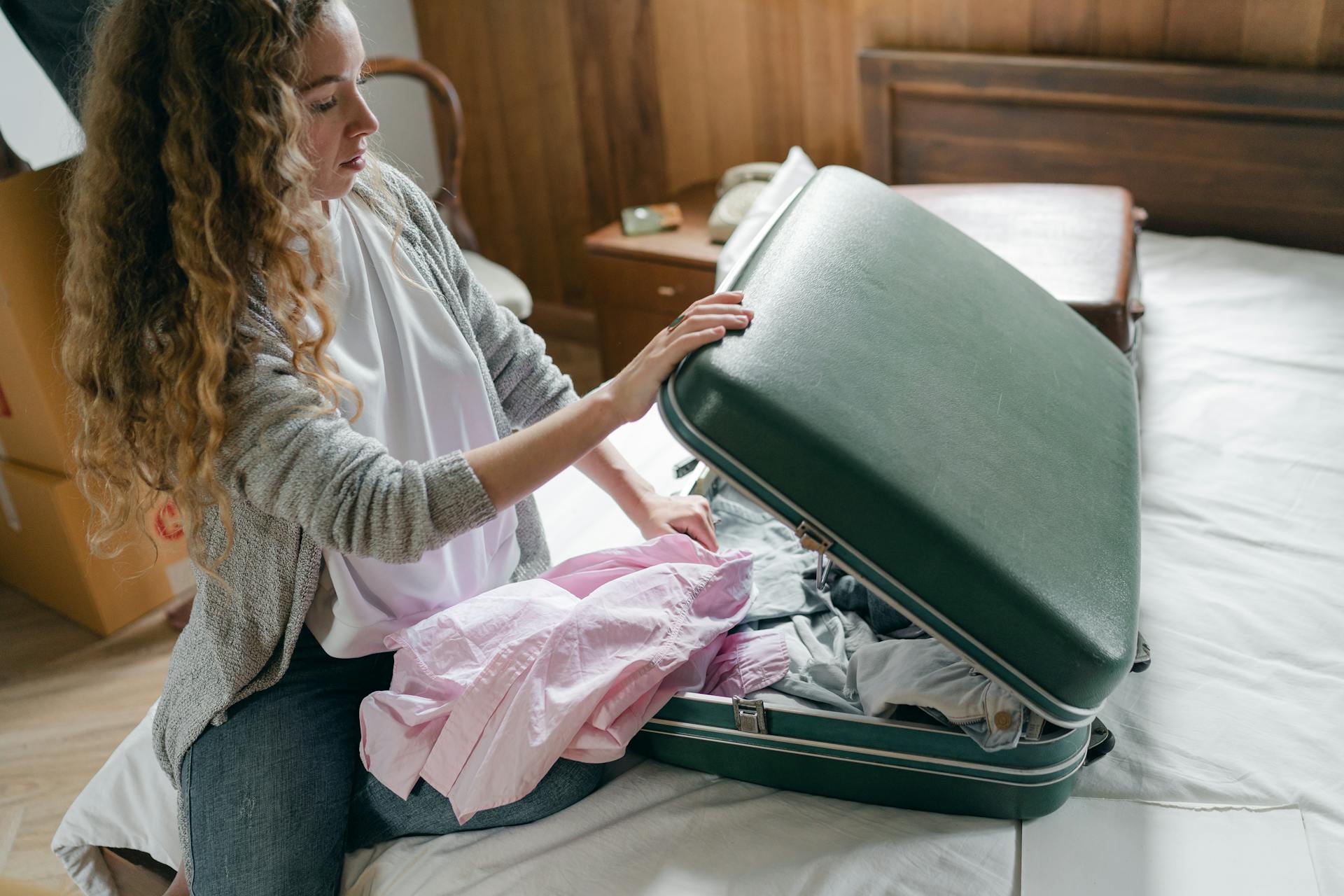 Une femme rangeant des vêtements dans une valise | Source : Pexels
