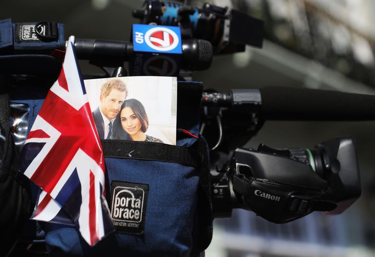 Un drapeau de l'Union Jack et une photo d'Harry et Meghan passent devant une caméra de télévision lors du mariage du prince Harry à Mme Meghan Markle Chapelle Saint-Georges, château de Windsor, le 19 mai 2018 à Windsor, en Angleterre. | Source : Getty Images
