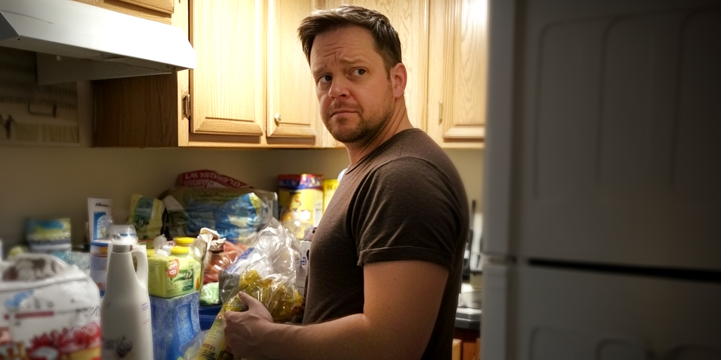 Un homme debout dans une cuisine à côté d'articles d'épicerie | Source : Midjourney