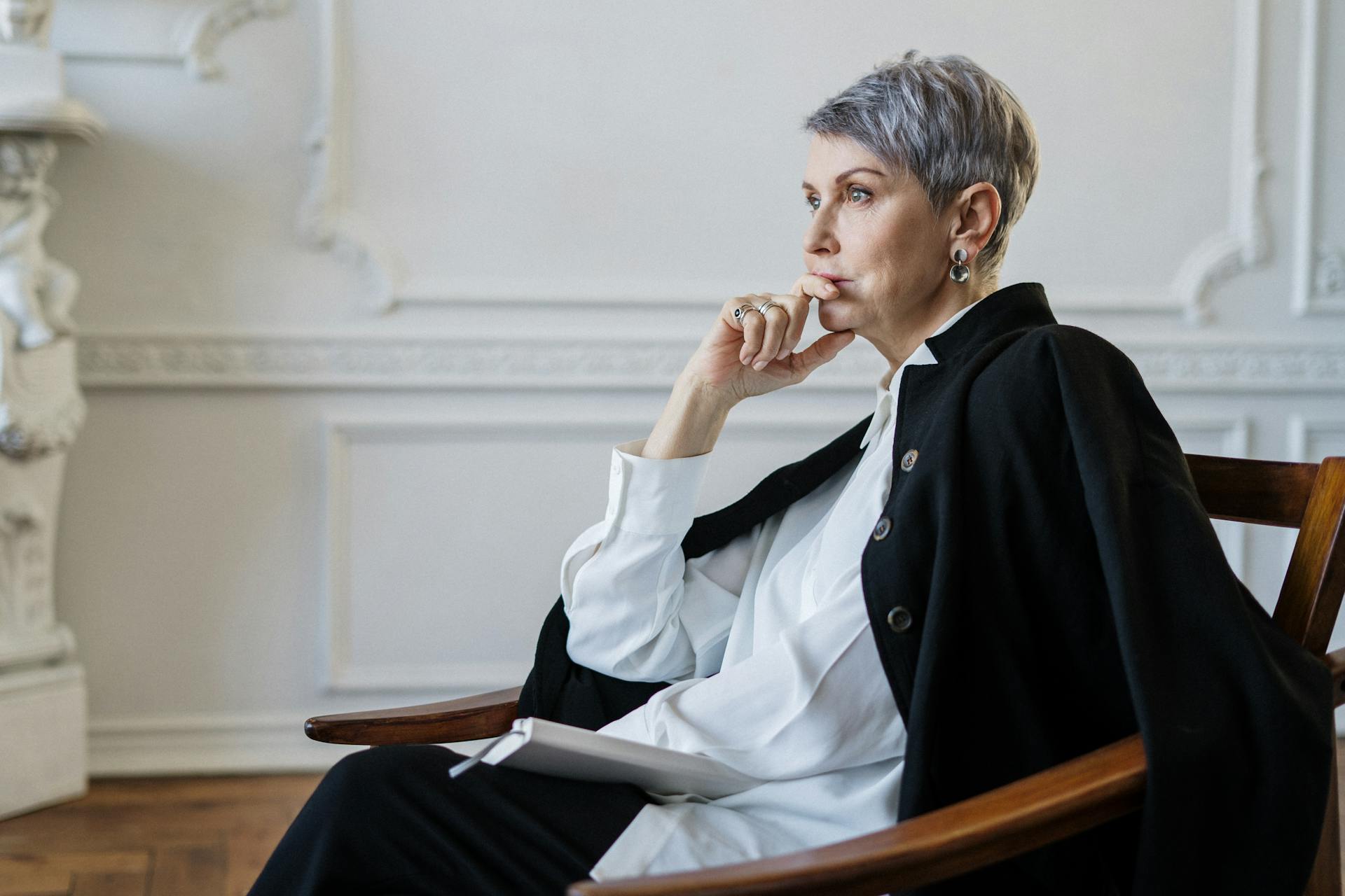 Une femme vêtue d'une chemise blanche et d'un blazer noir est assise sur une chaise et écoute attentivement | Source : Pexels