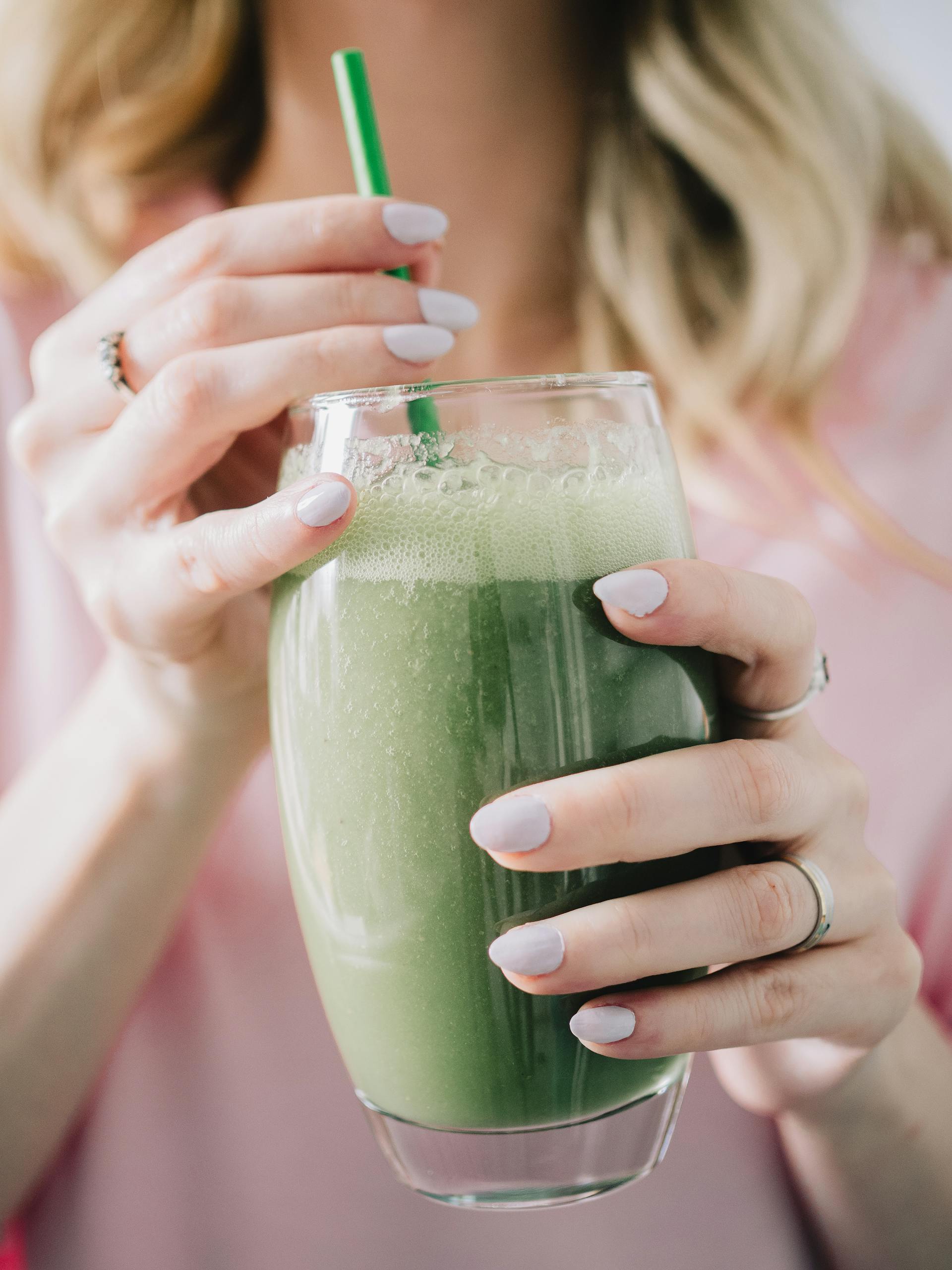 Une femme tenant un verre de smoothie vert | Source : Pexels