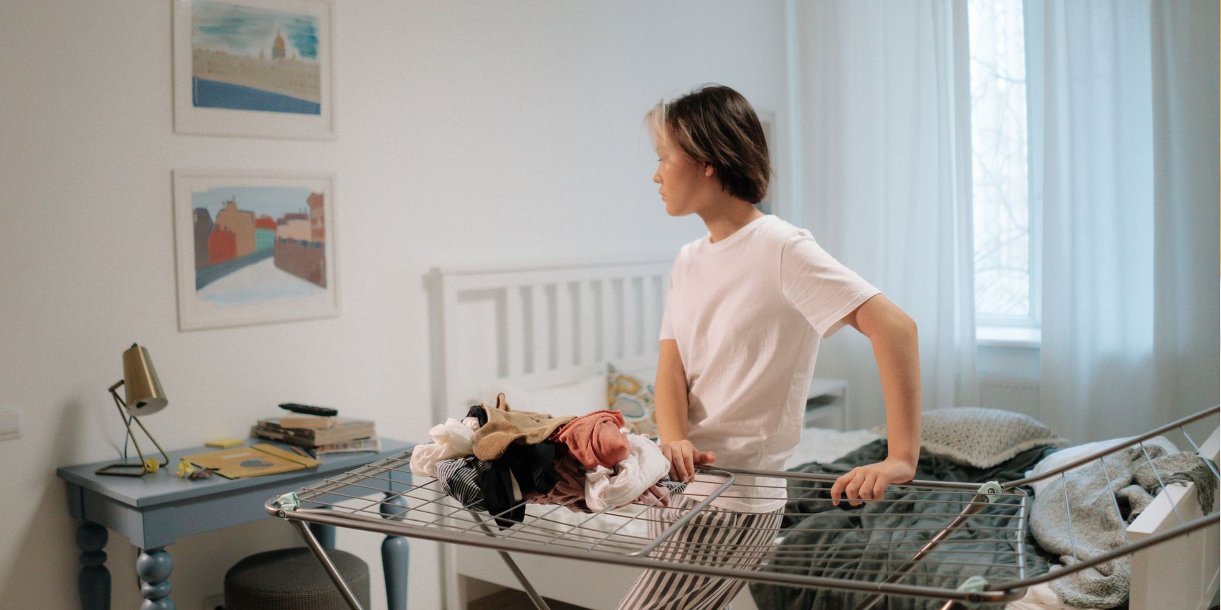 Une jeune femme se tient debout dans une chambre élégante, en train de ranger des vêtements sur un séchoir à linge | Source : Pexels