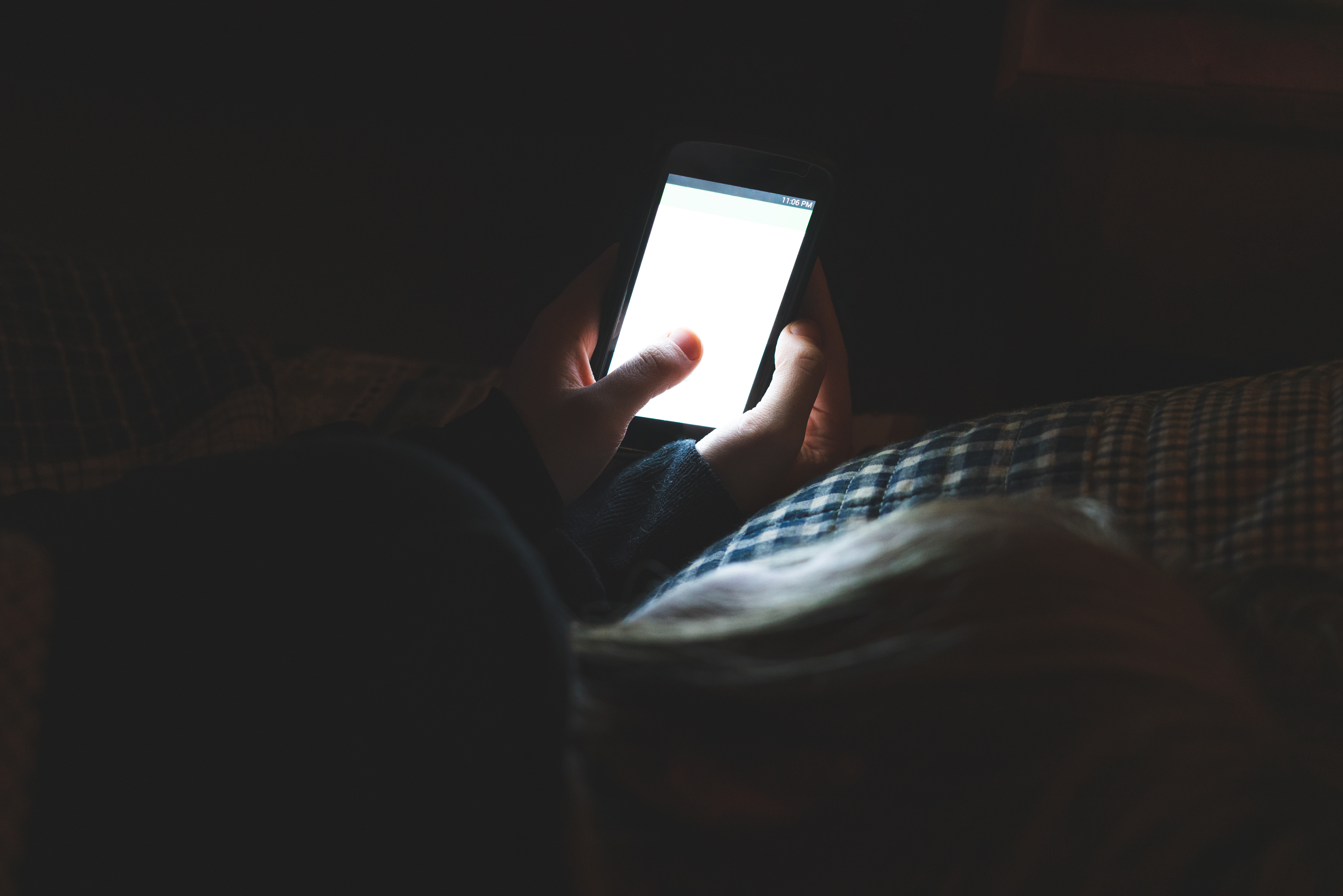 Une personne tenant un smartphone dans une pièce sombre | Source : Shutterstock