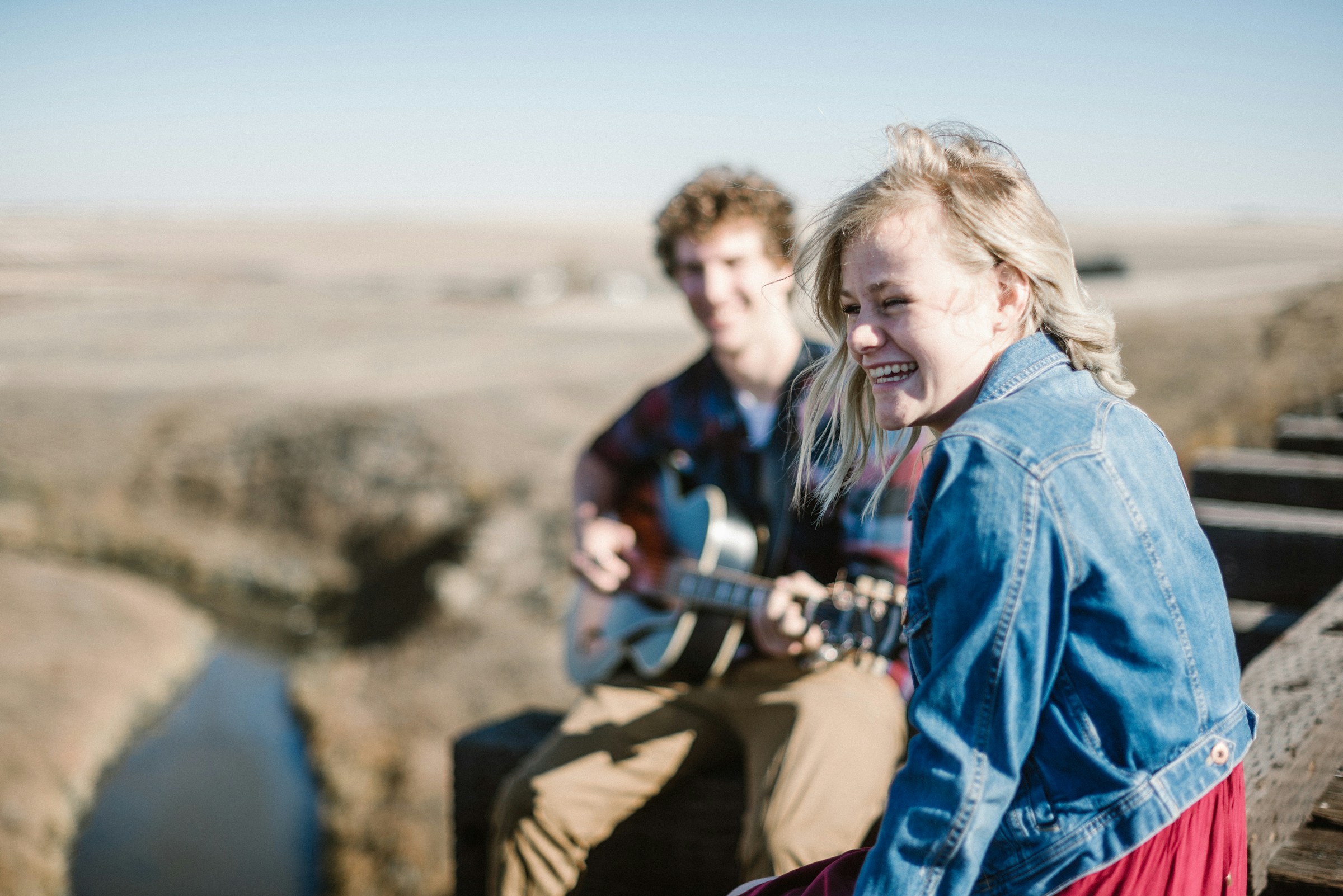 Une femme sourit alors qu'elle est assise à côté d'un homme qui joue de la guitare | Source : Unsplash