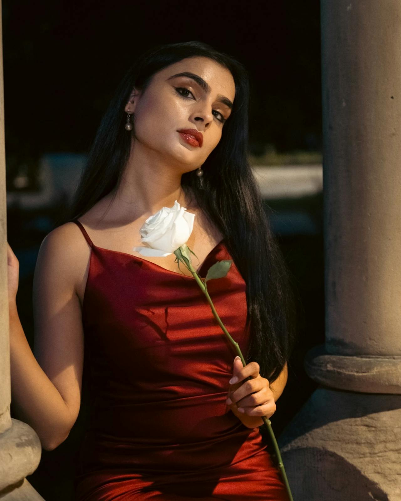 Une femme en robe rouge tenant une rose | Source : Pexels