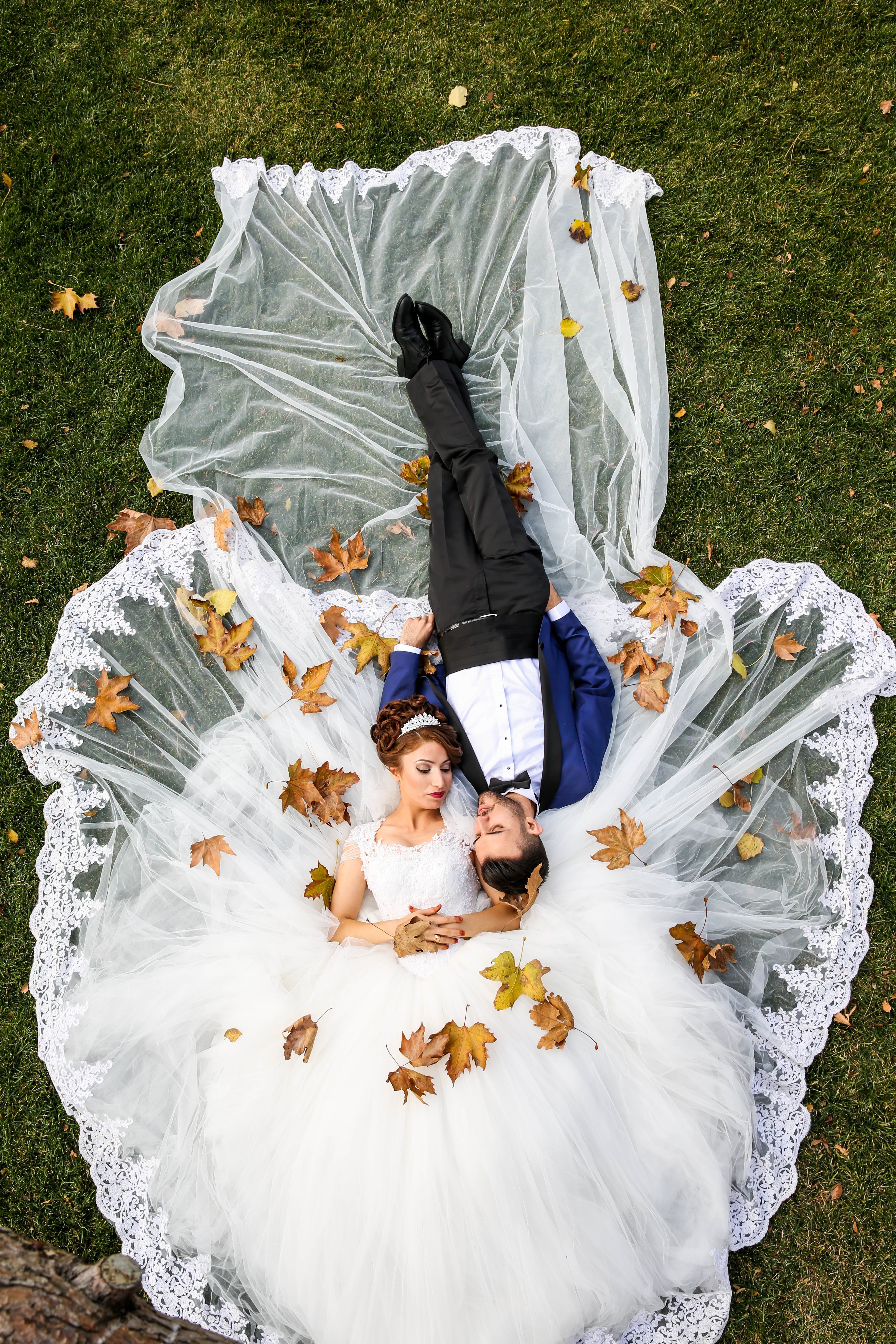 Un couple de jeunes mariés allongé sur l'herbe dans les vêtements de mariage | Source : Pexels