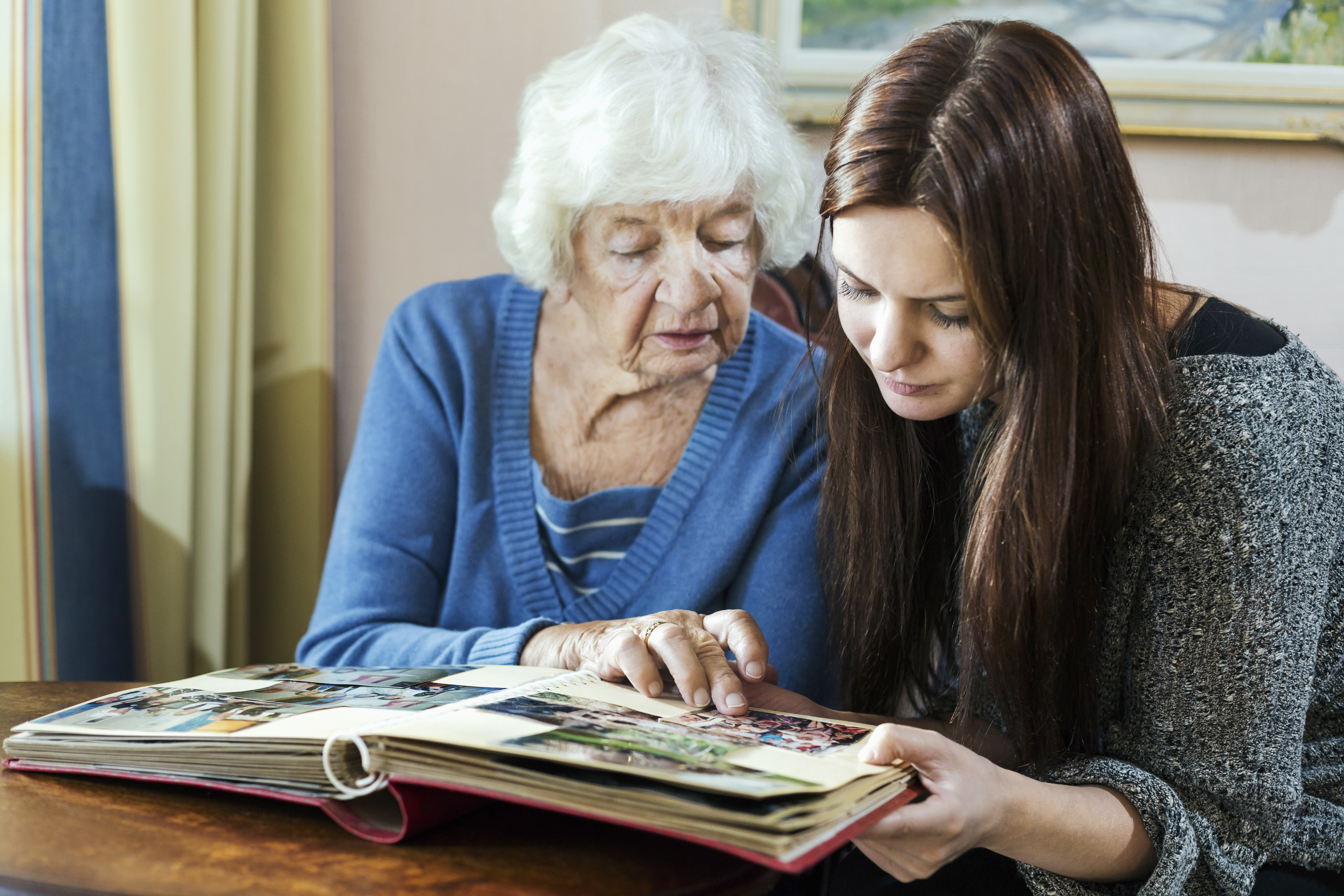 Grand-mère et petite-fille regardant un album photo dans une maison | Source : Getty Images