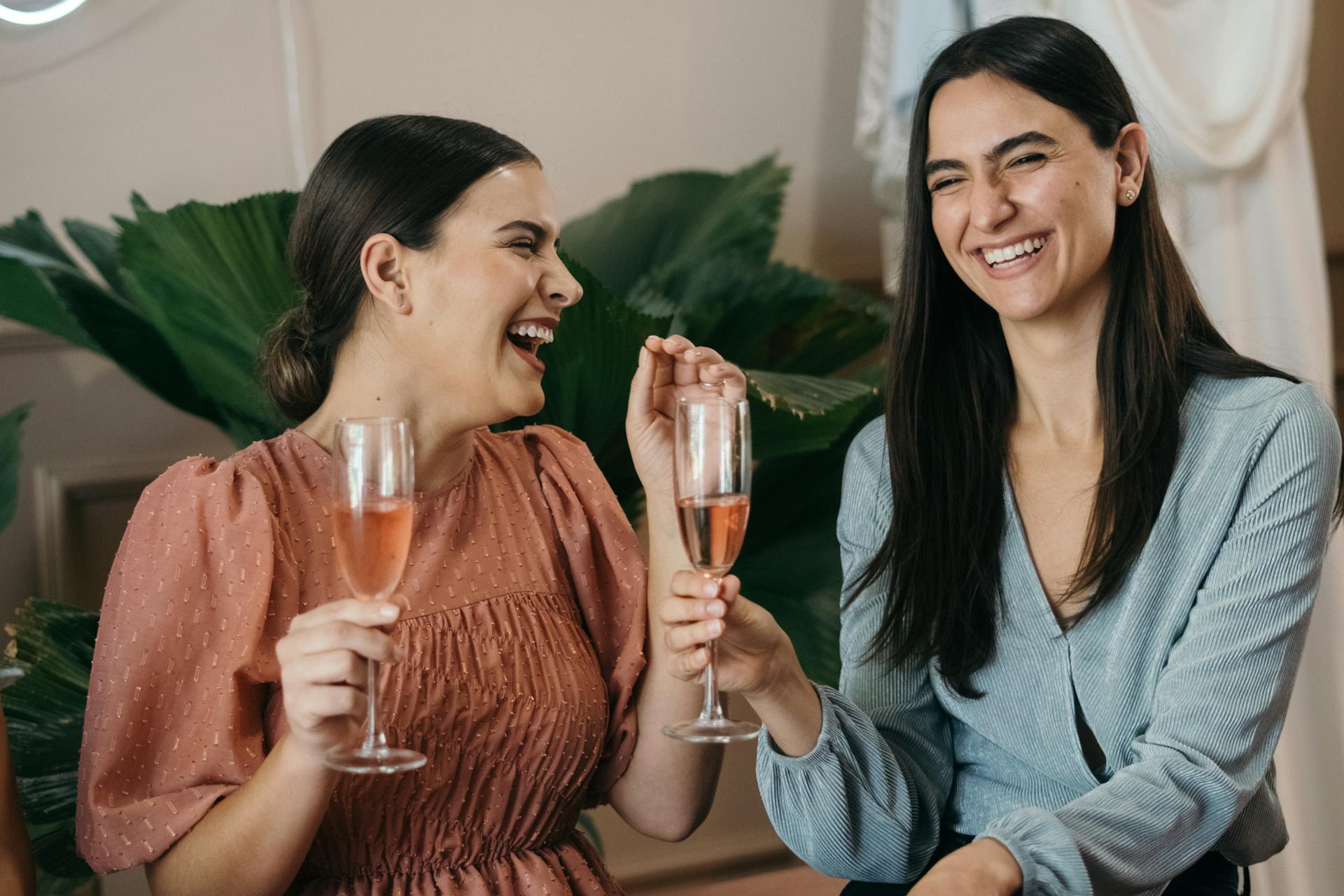 Deux femmes rient en tenant des boissons lors d'une fête | Source : Pexels