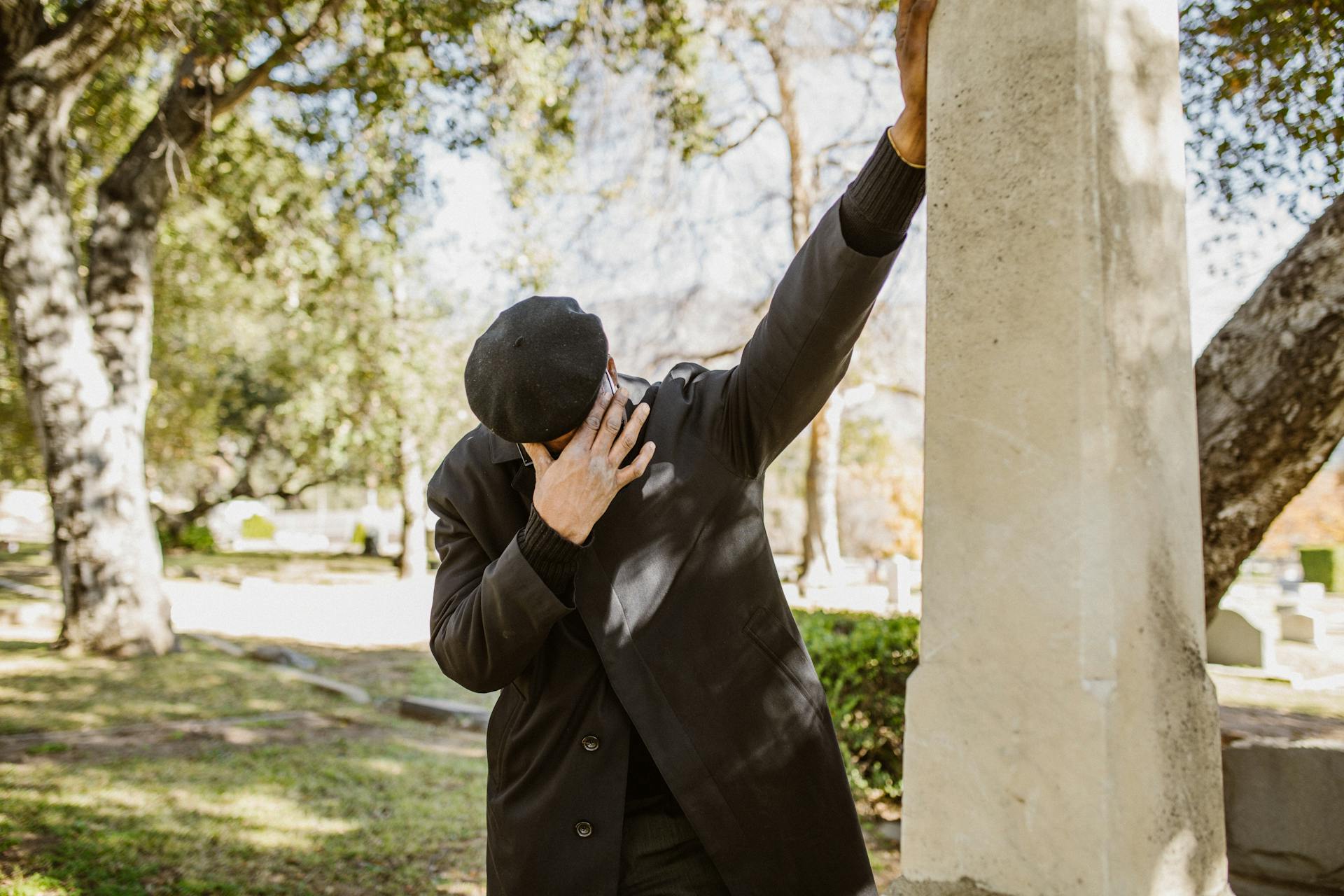 Gros plan sur un homme en costume noir qui pleure dans un cimetière | Source : Pexels