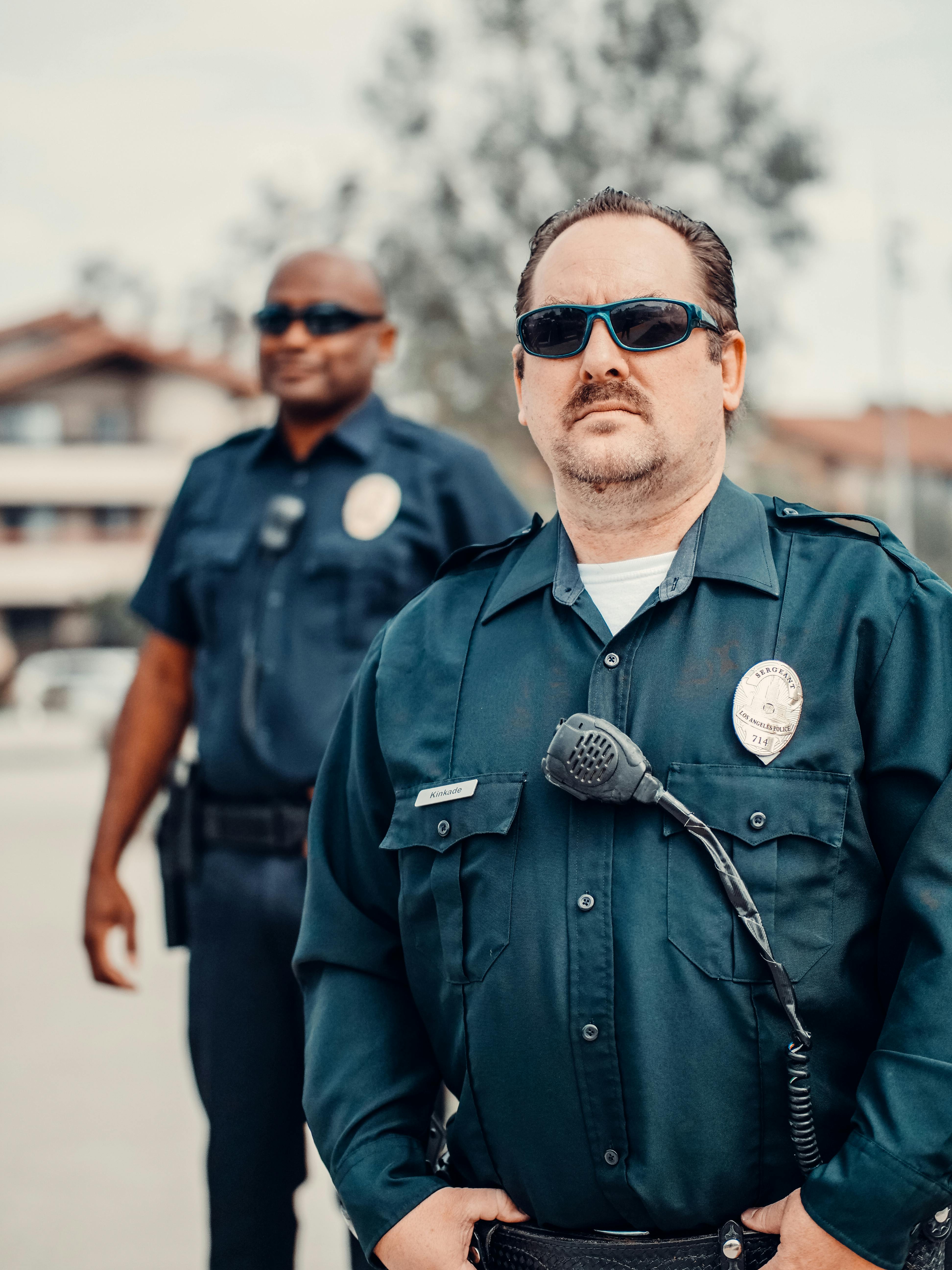 Un policier à l'air sombre se tenant derrière un collègue | Source : Pexels