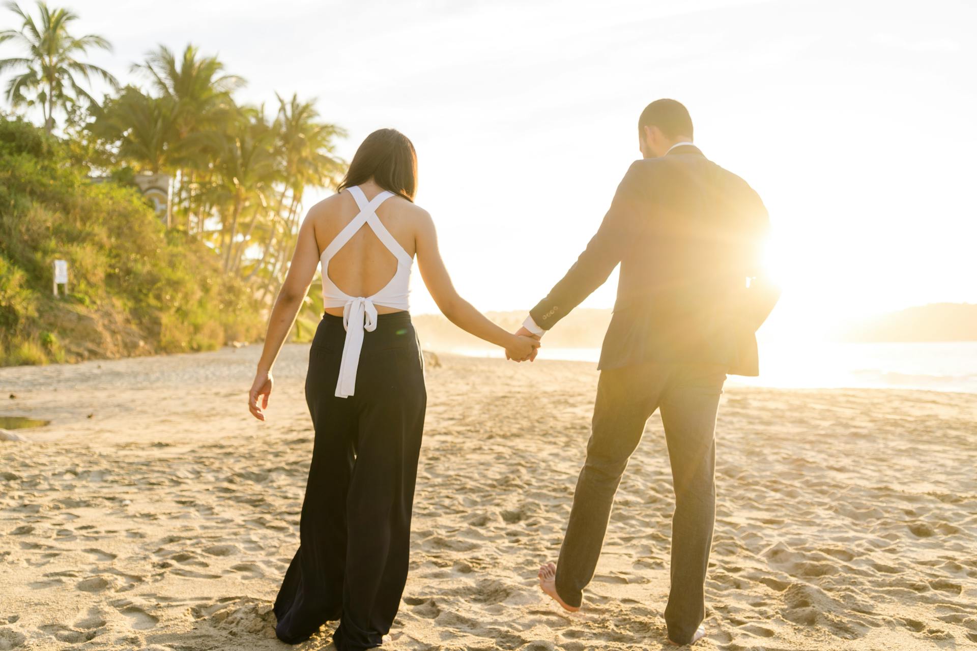 Vue arrière d'un couple marchant sur la plage | Source : Pexels