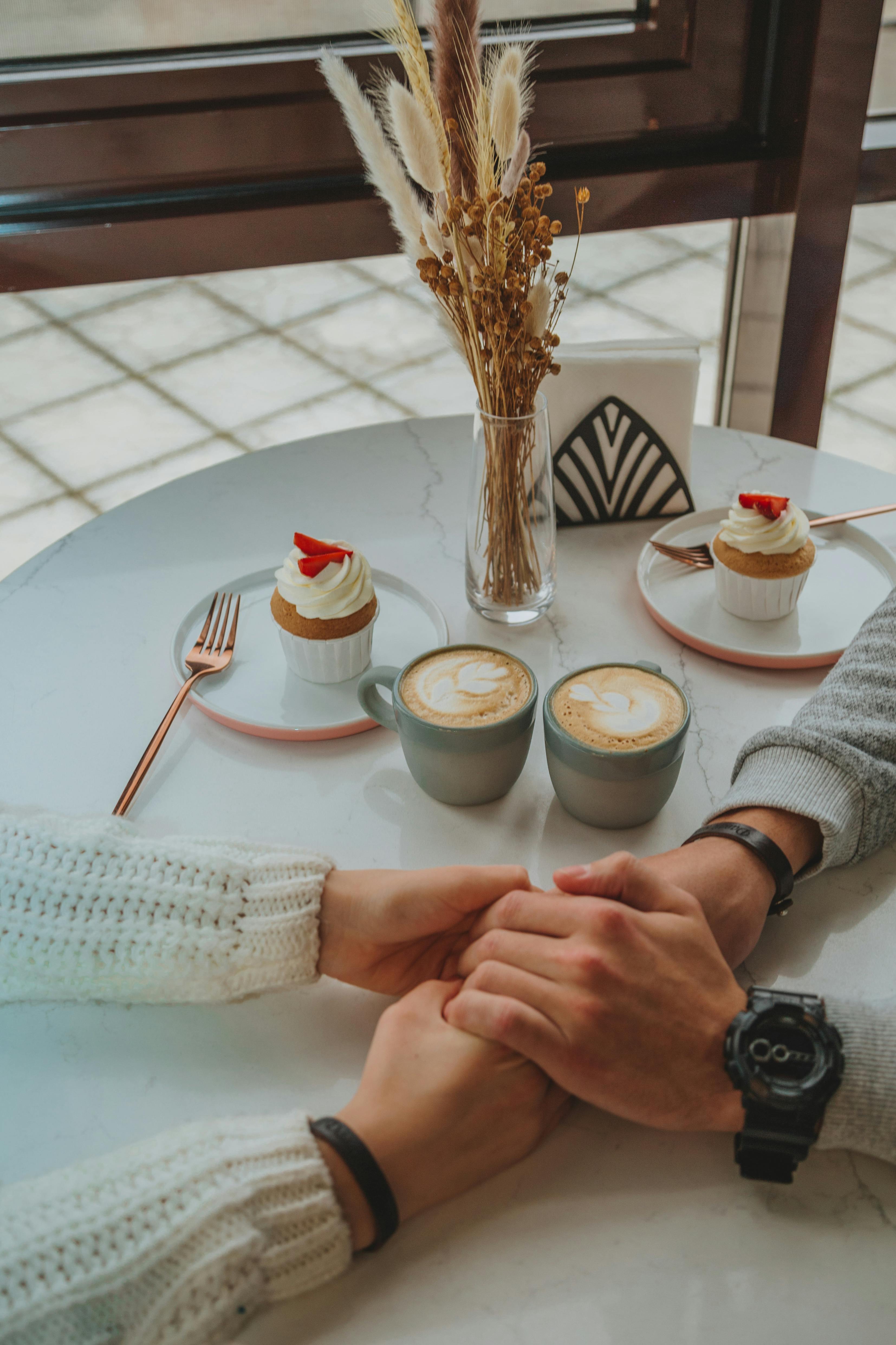 Un couple se tenant par la main tout en dégustant un dessert et un café | Source : Pexels
