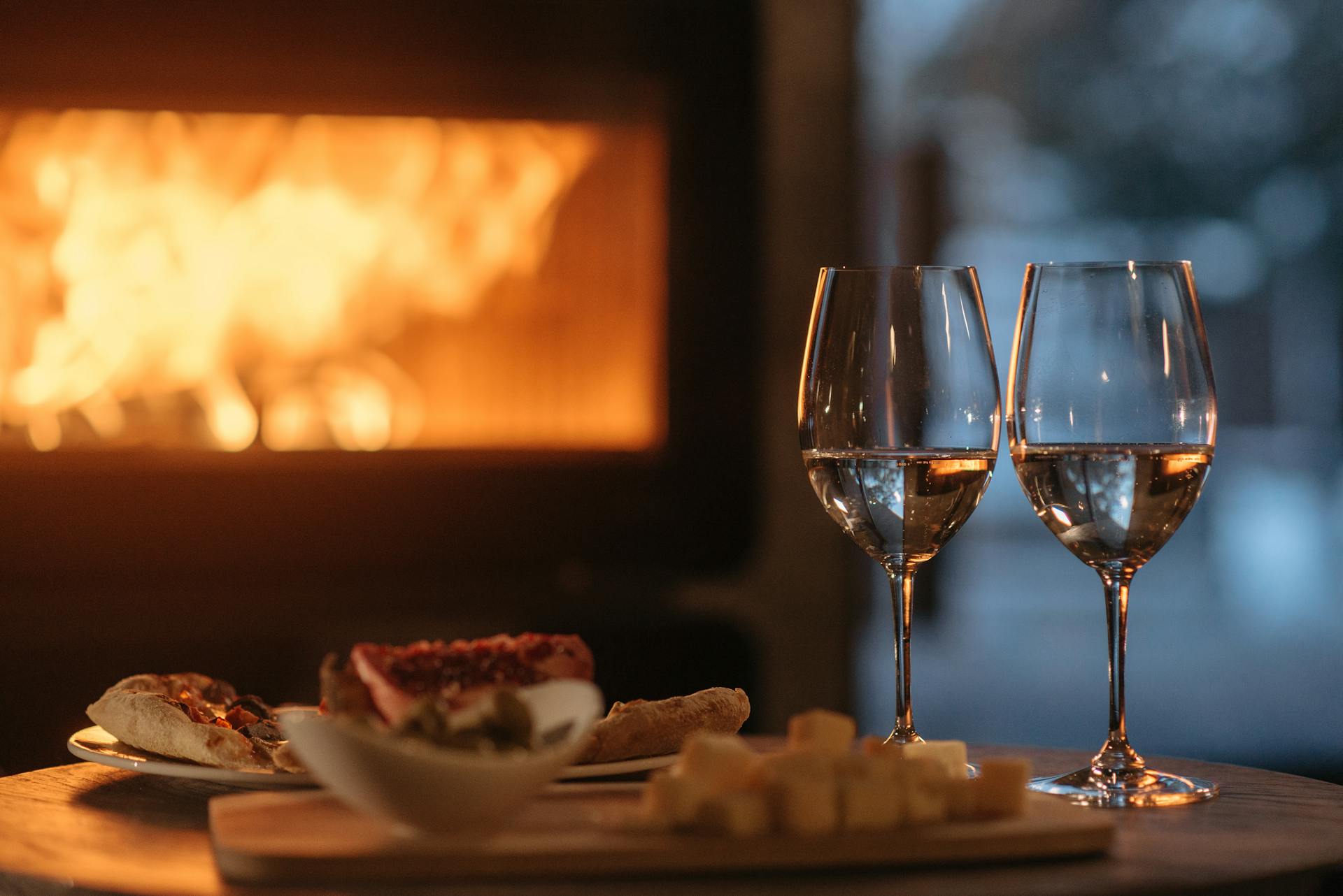 Une photo montrant deux verres à vin posés à côté d'une assiette de nourriture lors d'une soirée d'hiver confortable | Source : Pexels