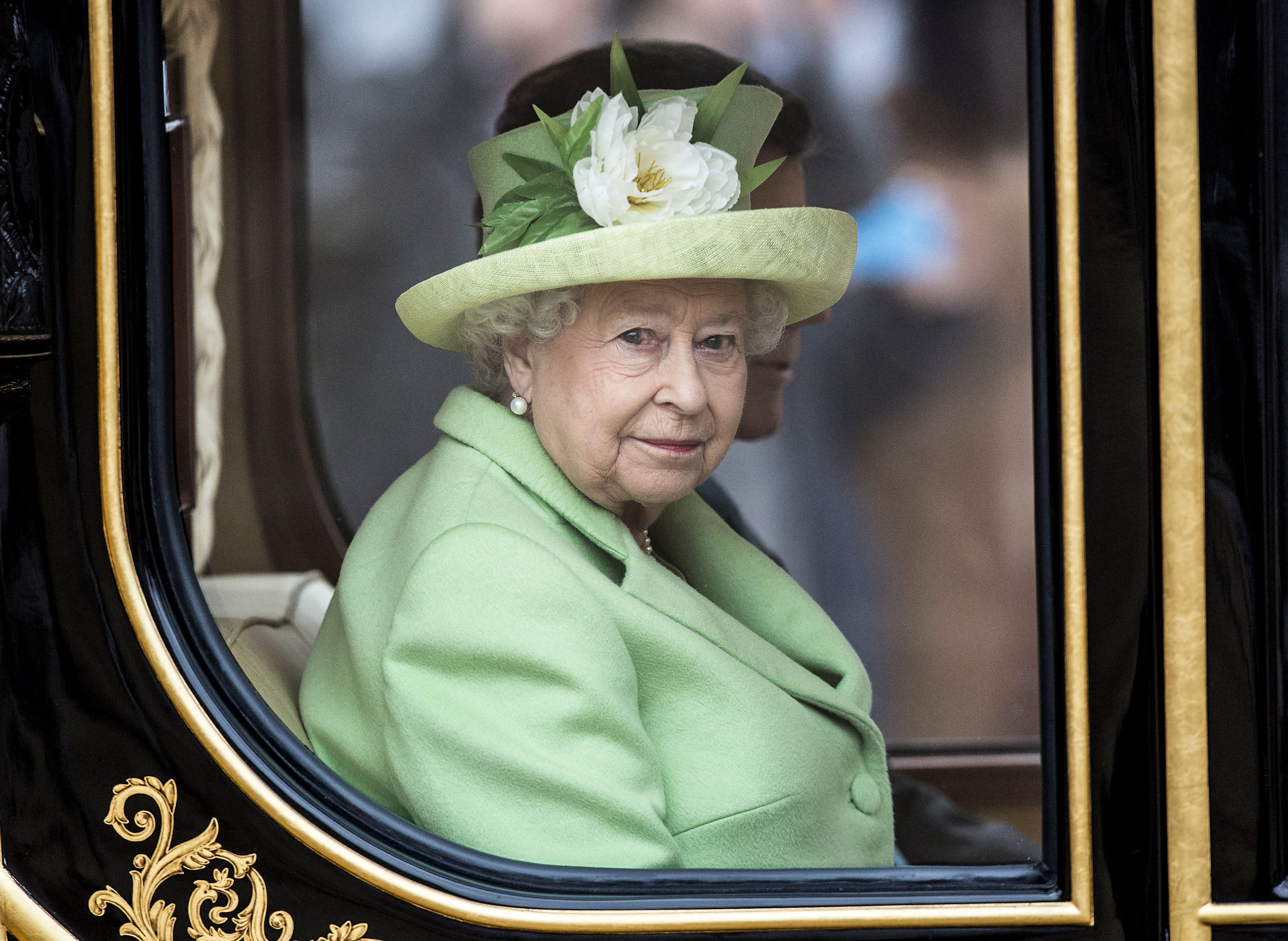 Assise à l'intérieur du carrosse d'État Diamond Jubilee, la reine Elizabeth II voyage en compagnie de l'ancien président colombien Juan Manuel Santos lors de sa visite officielle au Royaume-Uni en 2016. Vêtue de vert et coiffée d'un chapeau à fleurs, la monarque laisse entrevoir son œil rouge à travers la fenêtre du carrosse.