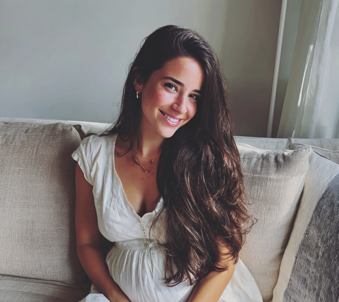 Une femme enceinte souriante portant une robe blanche | Source : Midjourney