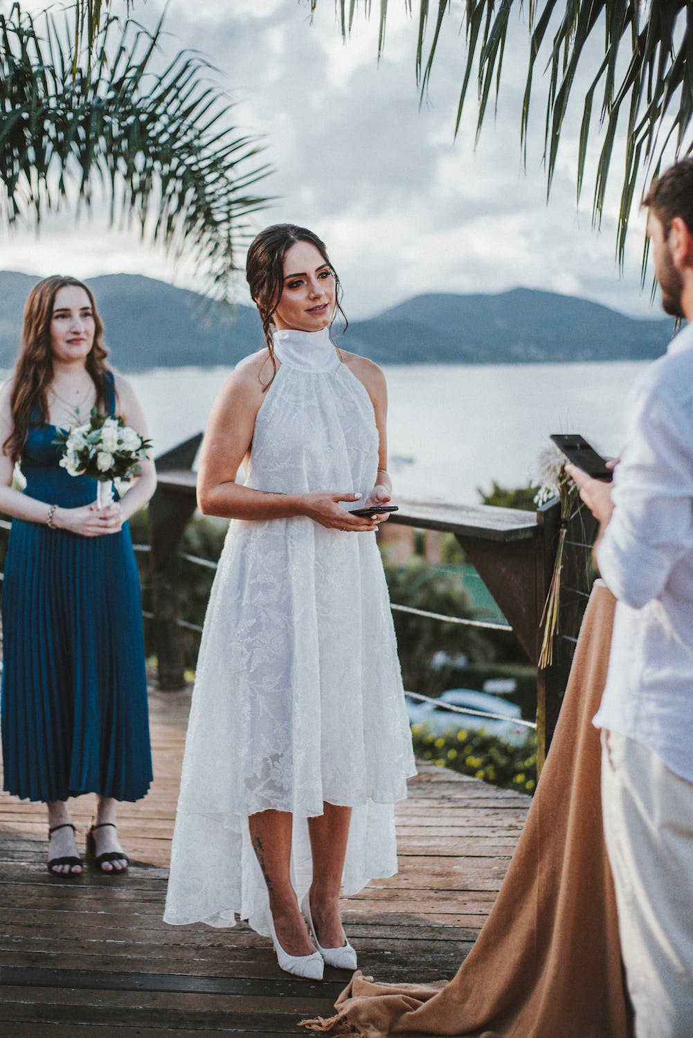 Une mariée en blanc et sa demoiselle d'honneur devant le marié en blanc | Source : Pexels