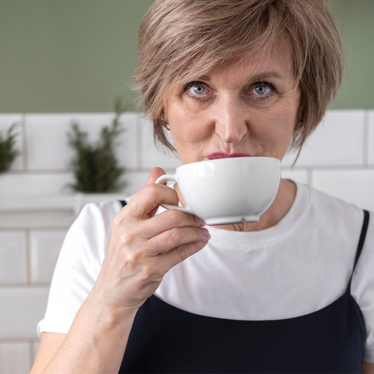 Une femme âgée souriante tenant une tasse en céramique | Source : Freepik